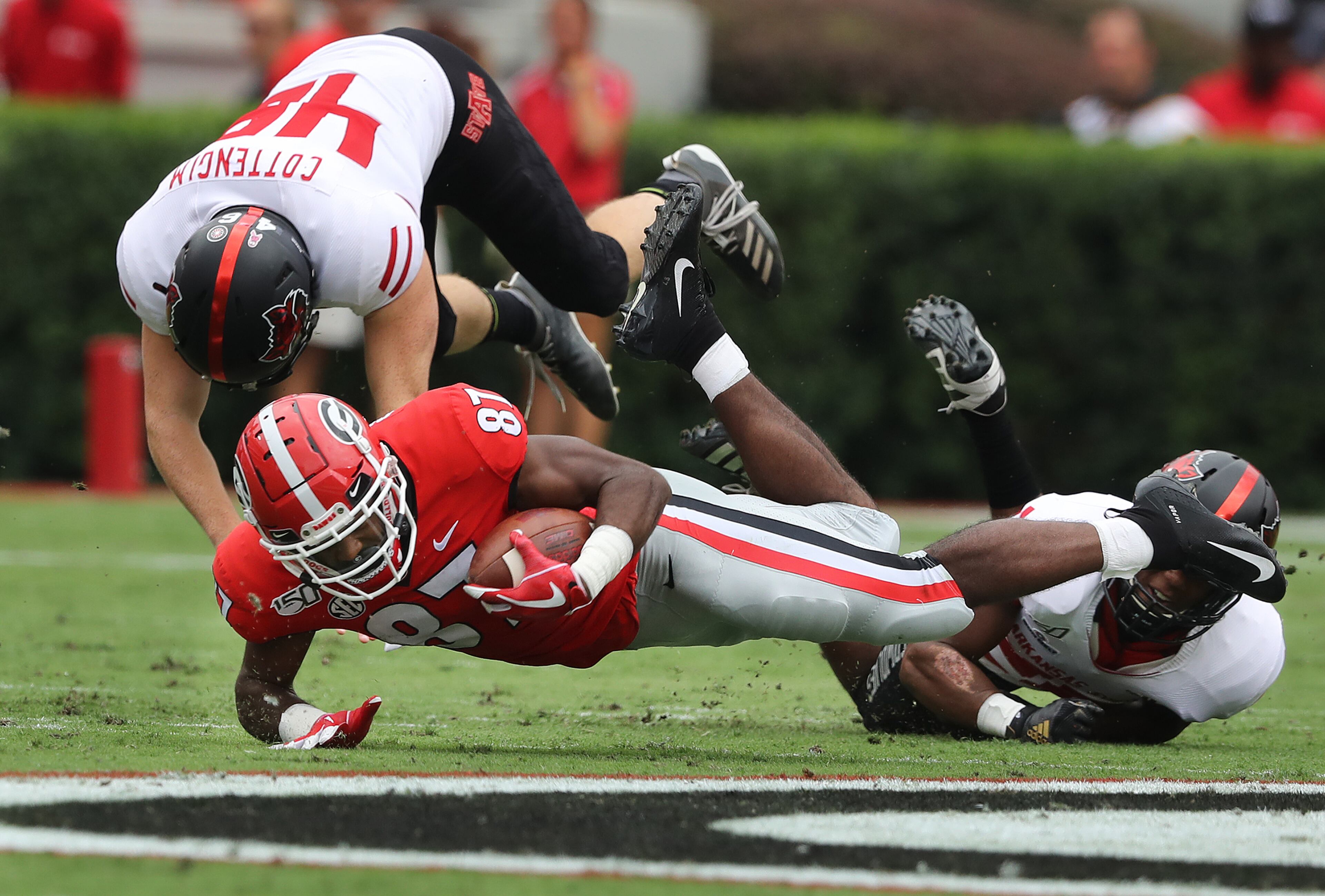 Georgia wide receiver Tyler Simmons stretches for extra yardage as he is tackled by Arkansas State defenders. Curtis Compton/ccompton@ajc.com