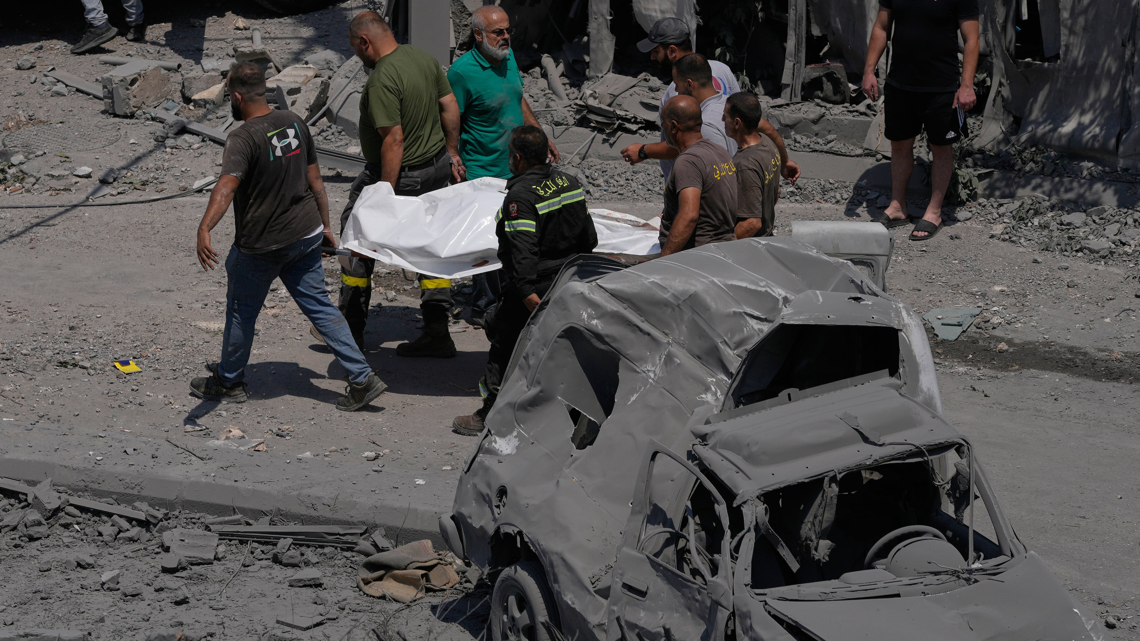 Rescue workers carry a plastic bag, containing the body of a person who was killed at a house that was hit by an Israeli airstrike in Deir al-Zahrani village, southern Lebanon, Saturday, Aug. 15, 2026. (AP Photo/Mohammed Zaatari)