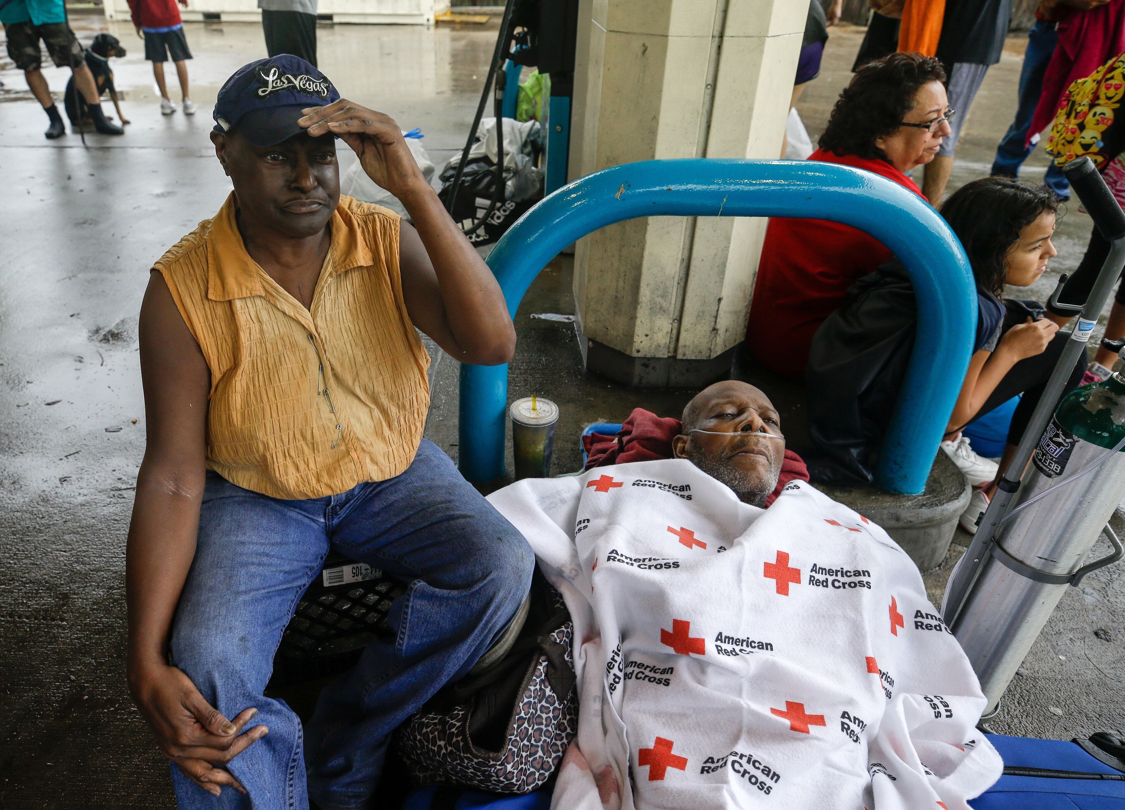 Ruby Young waits with her husband, Claude Young, after being rescued from their flooded home by boat and taken to a pickup point along Edgebrook Sunday, Aug. 27, 2017. The elderly man had many medical issues from a stroke in May. Rising floodwaters from the remnants of Hurricane Harvey chased thousands of people to rooftops or higher ground Sunday in Houston, overwhelming rescuers who fielded countless desperate calls for help. ( Melissa Phillip/Houston Chronicle via AP)
