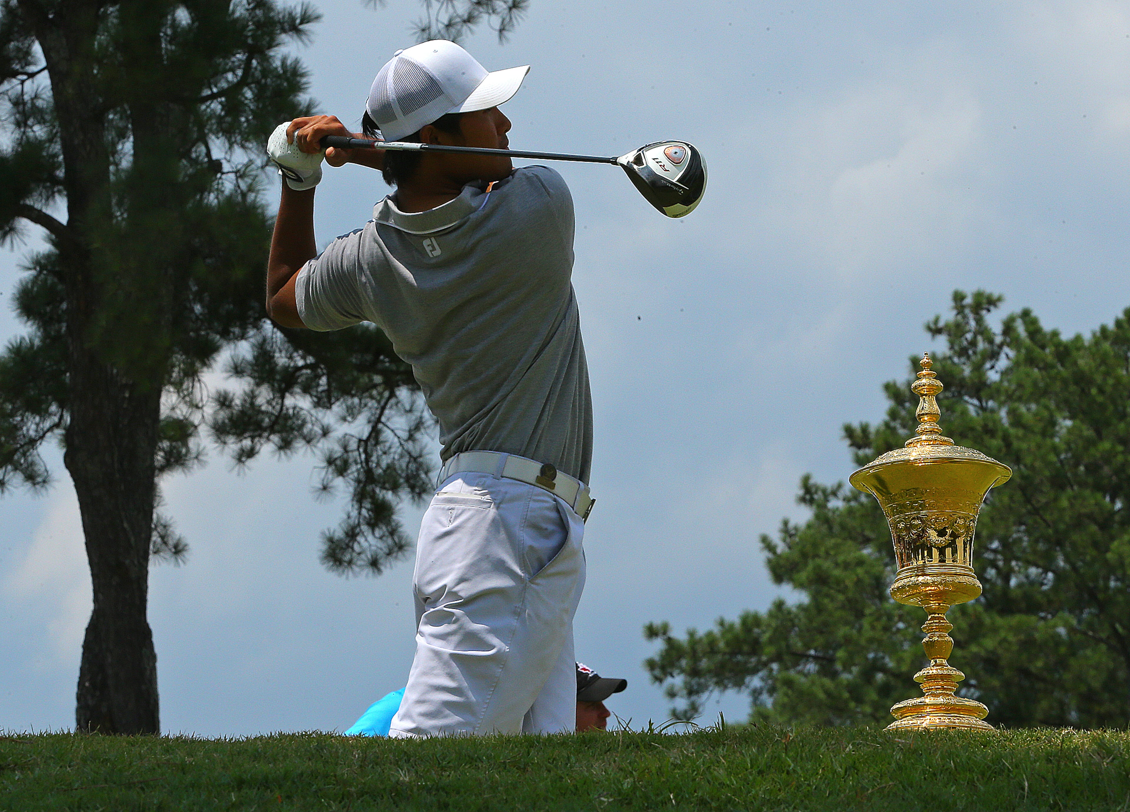 The trophy sits on the tee box as Gunn Yang, San Diego, California, tees off on the first hole during the afternoon round of the 36-hole championship match of the 2014 U.S. Amateur Championship at Atlanta Athletic Club on Sunday, August 17, 2014, in Johns Creek.