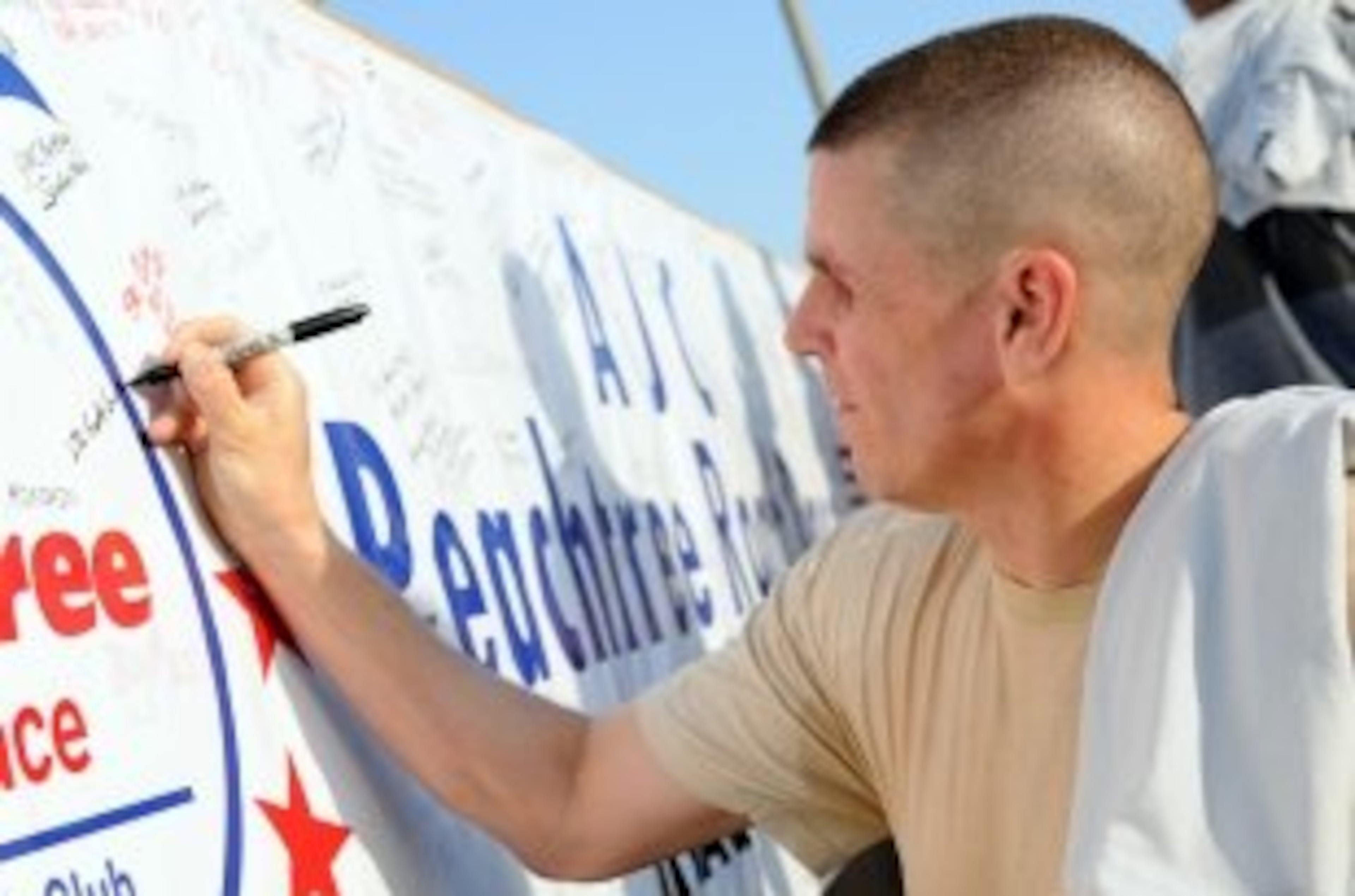 Lt. Col. Scott Gustafson, a Georgetown, Texas, native and deputy chief of Army Reserve Affairs, United States Forces-Iraq, signs a banner after participating in the AJC Peachtree Road Race in Baghdad.