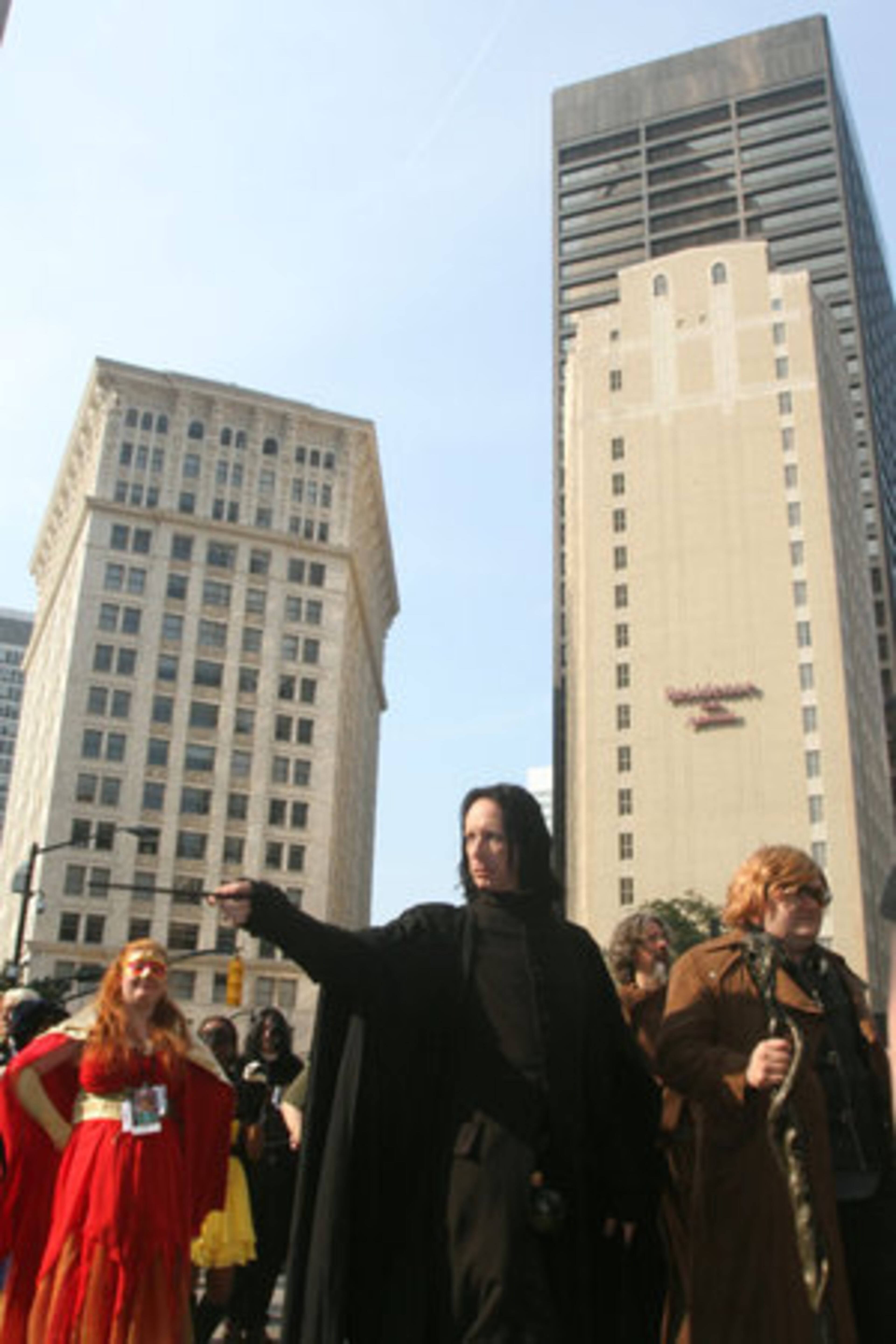 Severus Snape points his magic want at parade watchers.