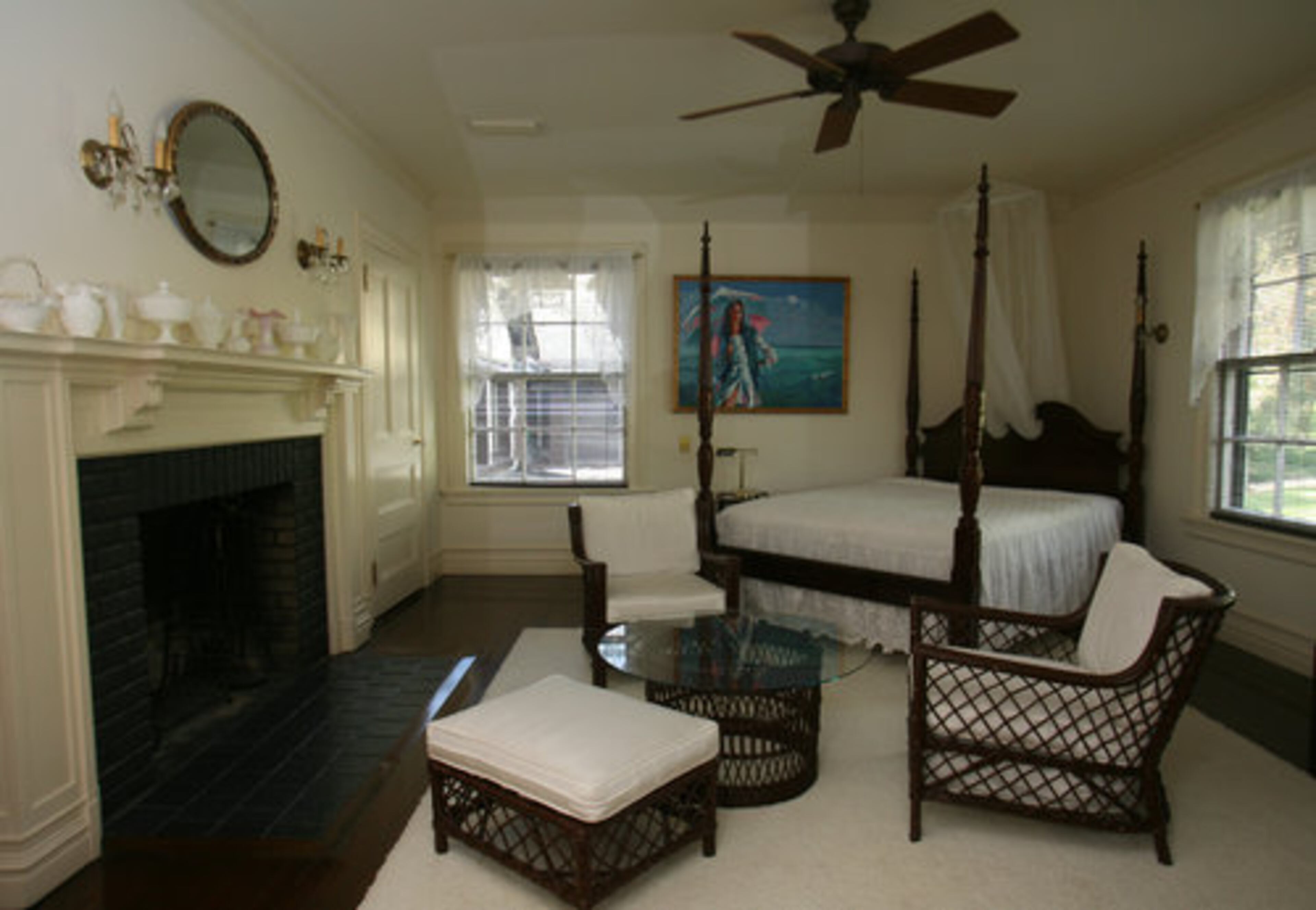 This guest suite assumes a European provincial air in white with lace curtains on the windows and a graceful four-poster bed. The only splash of color in the room is provided by another of Rolf Kauka's exuberant portraits of his wife. "He had a very keen eye for lines and colors," Kauka said.