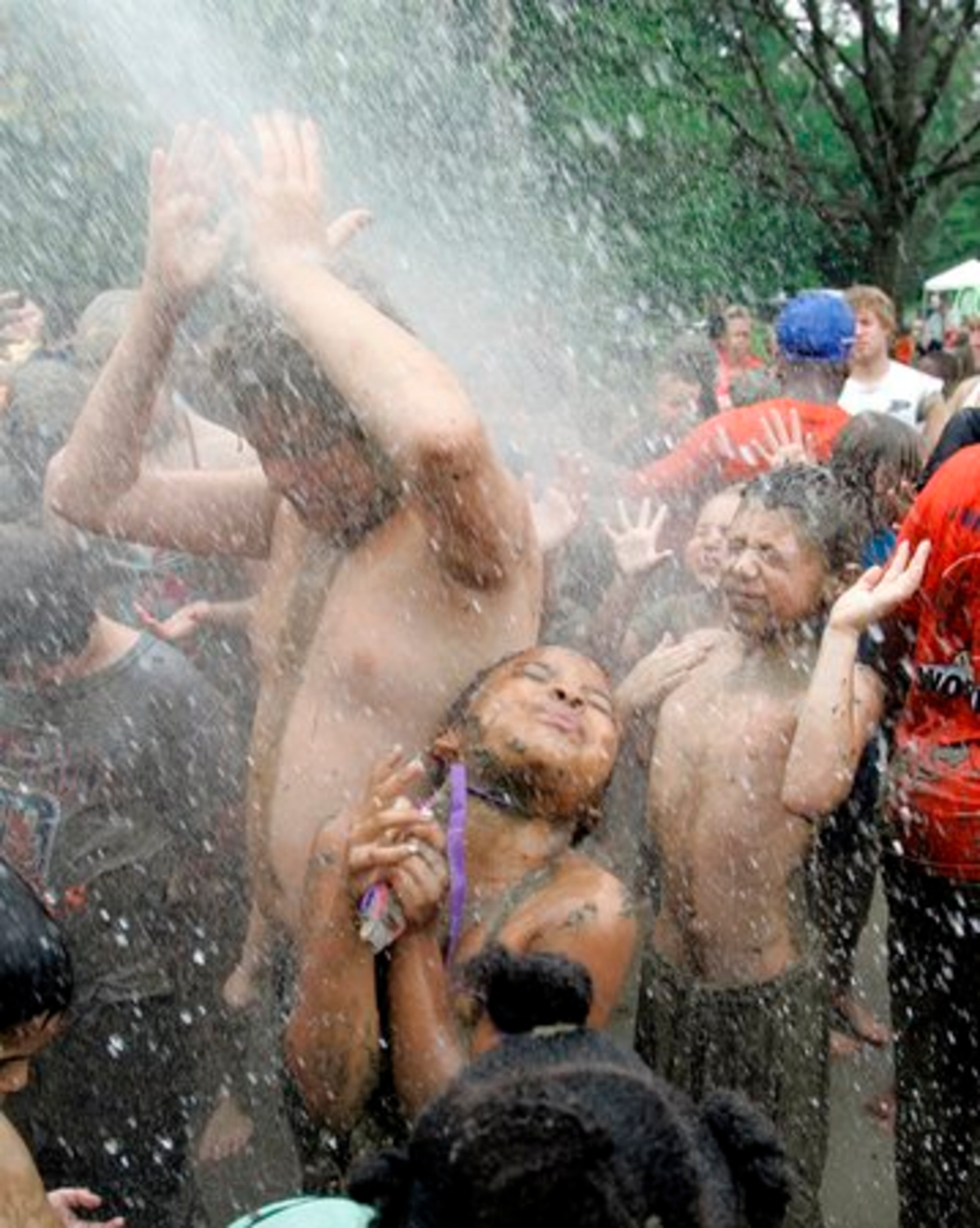 Children are hosed down by a Westland, Mich., pumper truck after playing in the mud.