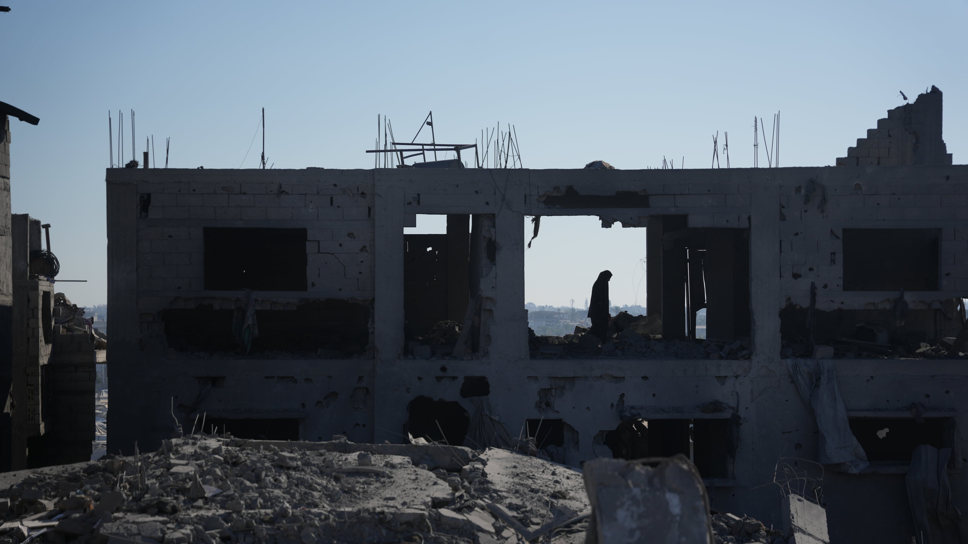 A Palestinian woman inspects a destroyed building following an Israeli airstrike in Deir al-Balah, central Gaza Strip, Sunday, July 19, 2026. (AP Photo/Abdel Kareem Hana)