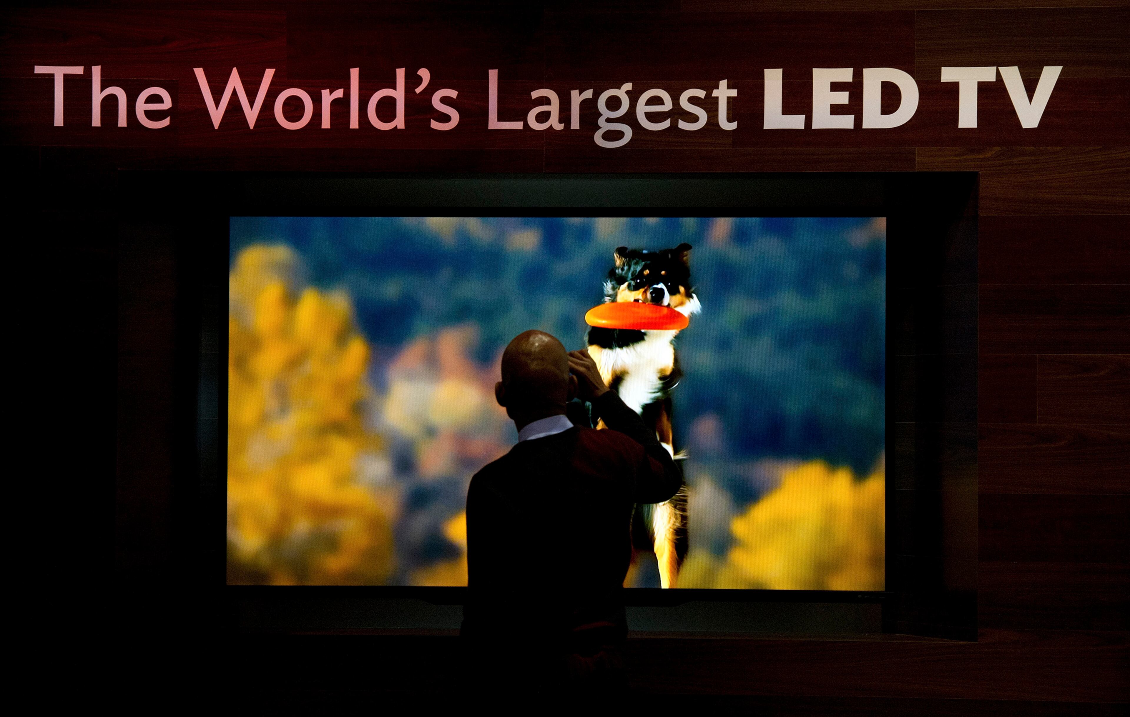 A spectator stops to take a photograph of a Sharp Corp., television on display prior to the 2013 Consumer Electronic Show. The 2013 CES trade show offers an array of entrepreneur focused exhibits, events and conference sessions for technology entrepreneurs.