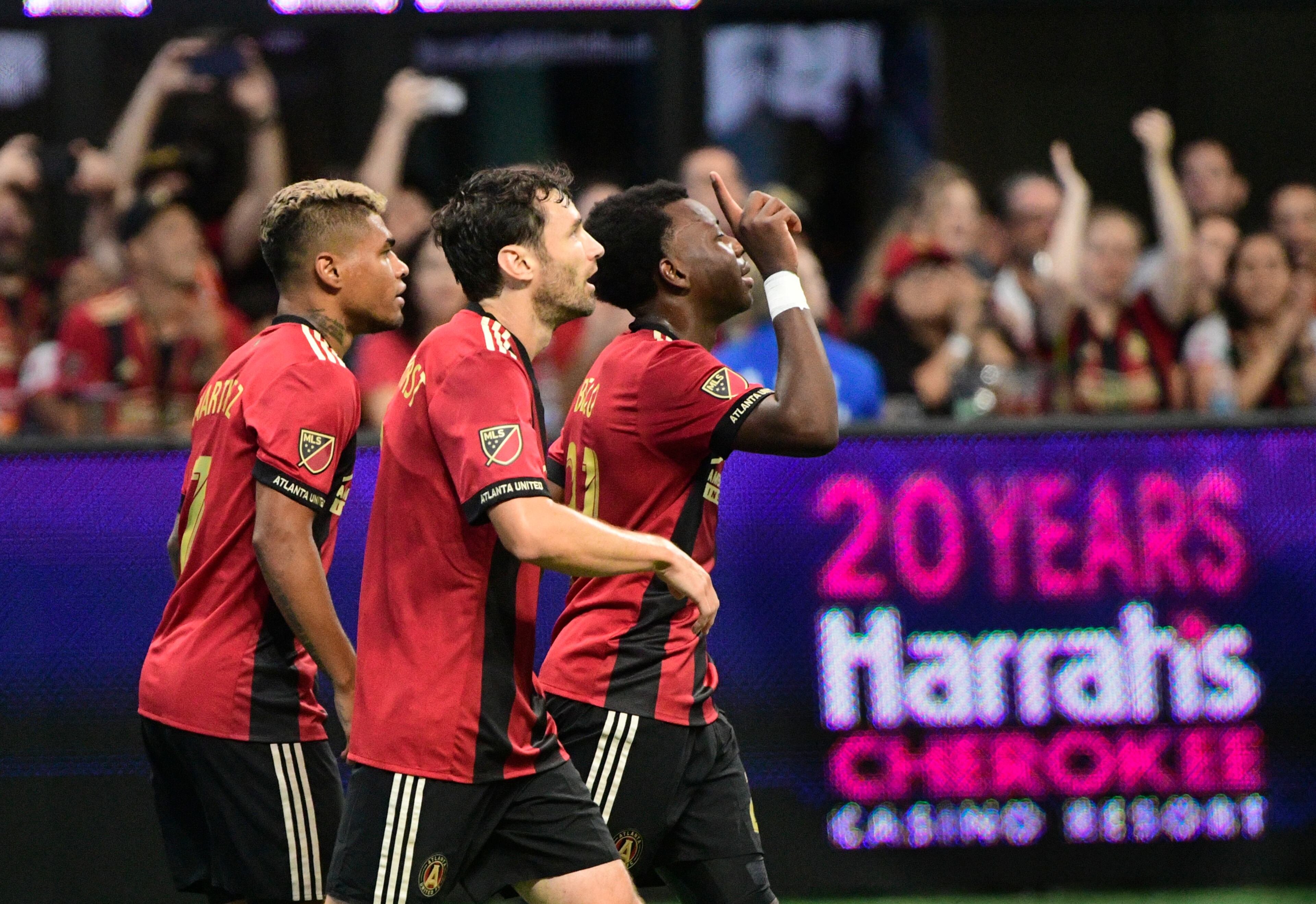 Atlanta United' George Bello points upward as he is followed by fellow defender Michael Parkhurst, and Josef Martinez, left, after scoring during the first half of an MLS soccer game against the New England Revolution, Saturday, Oct. 6, 2018. (John Amis)