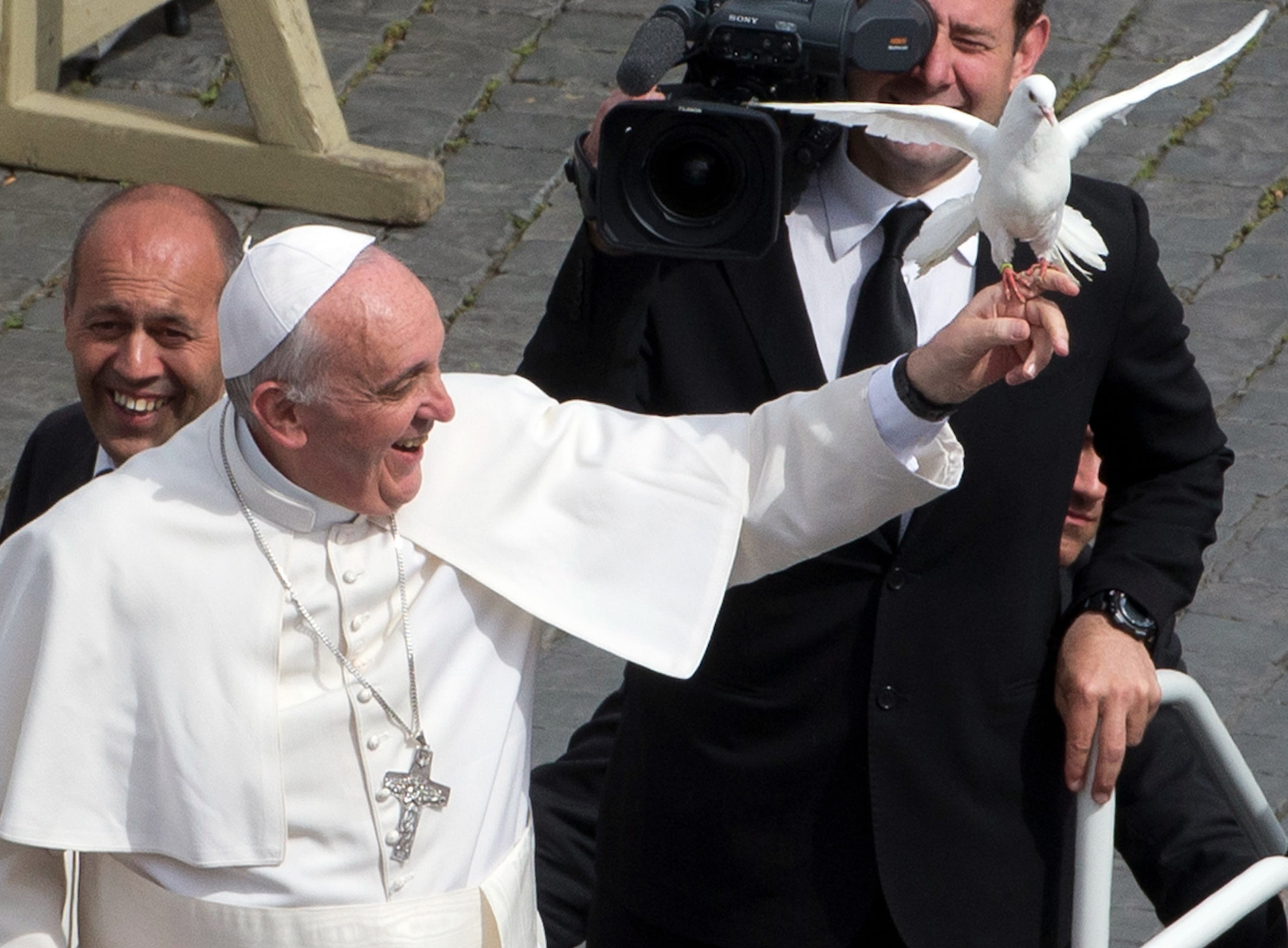 Pope Francis frees a dove during his weekly general audience in St. Peter Square at the Vatican, Wednesday, May 15, 2013. As Francis toured the square in his open-topped popemobile at his Wednesday audience with the public, someone at the edge of the crowd thrust a white bird cage at him. Looking puzzled, his security detail took the cage, containing a pair of white doves, and handed it to Francis. Without hesitation, the pope opened the cage door, thrust a hand inside and extracted one dove, and with a flick of his hand, sent the bird flying over the square. (AP Photo/Alessandra Tarantino)