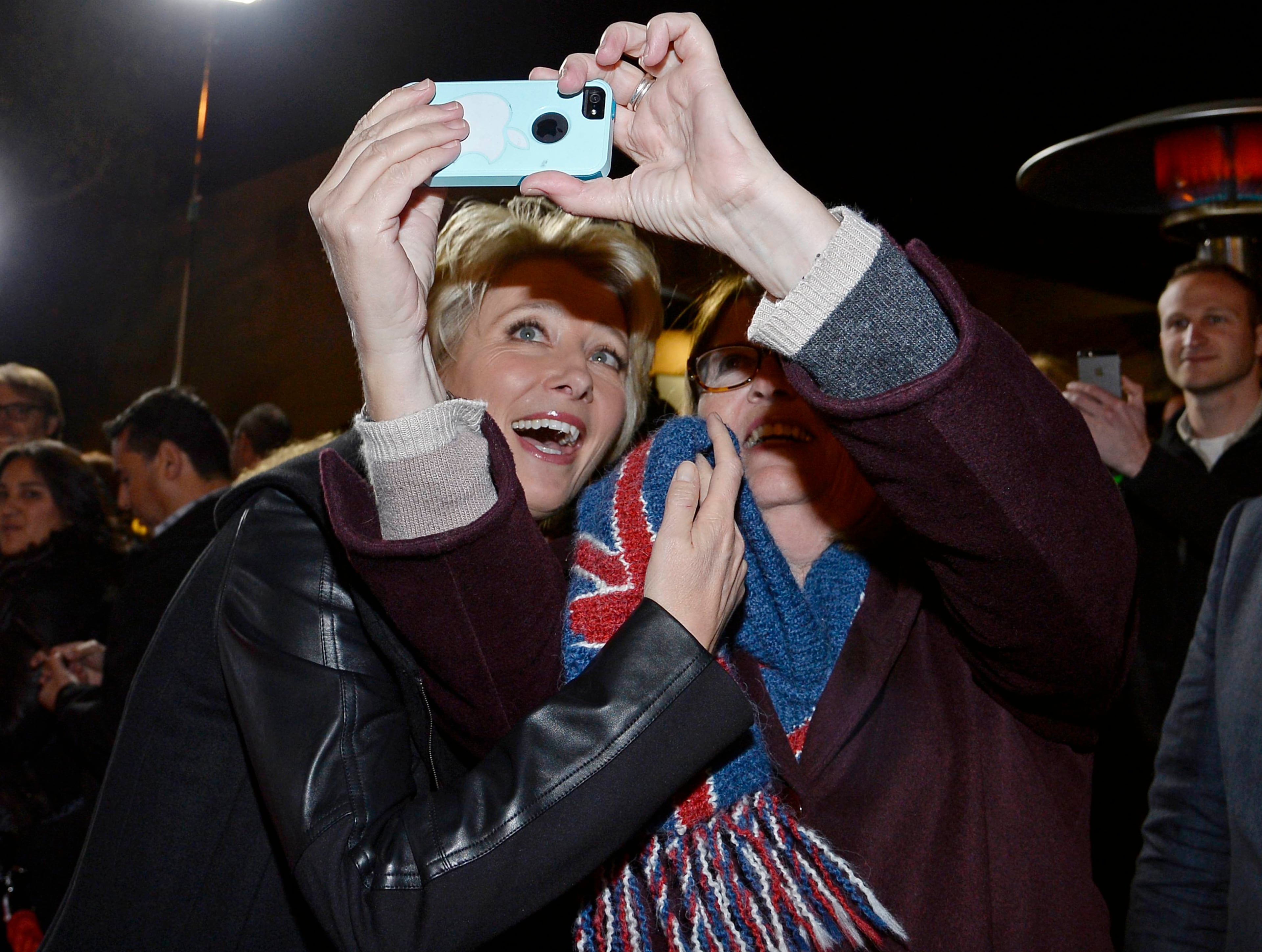 Cast member Emma Thompson (L) takes a selfie with a fan as she attends the film premiere of "Saving Mr. Banks" at the Walt Disney Studios in Burbank, California, December 9, 2013. REUTERS/Kevork Djansezian (UNITED STATES - Tags: ENTERTAINMENT)