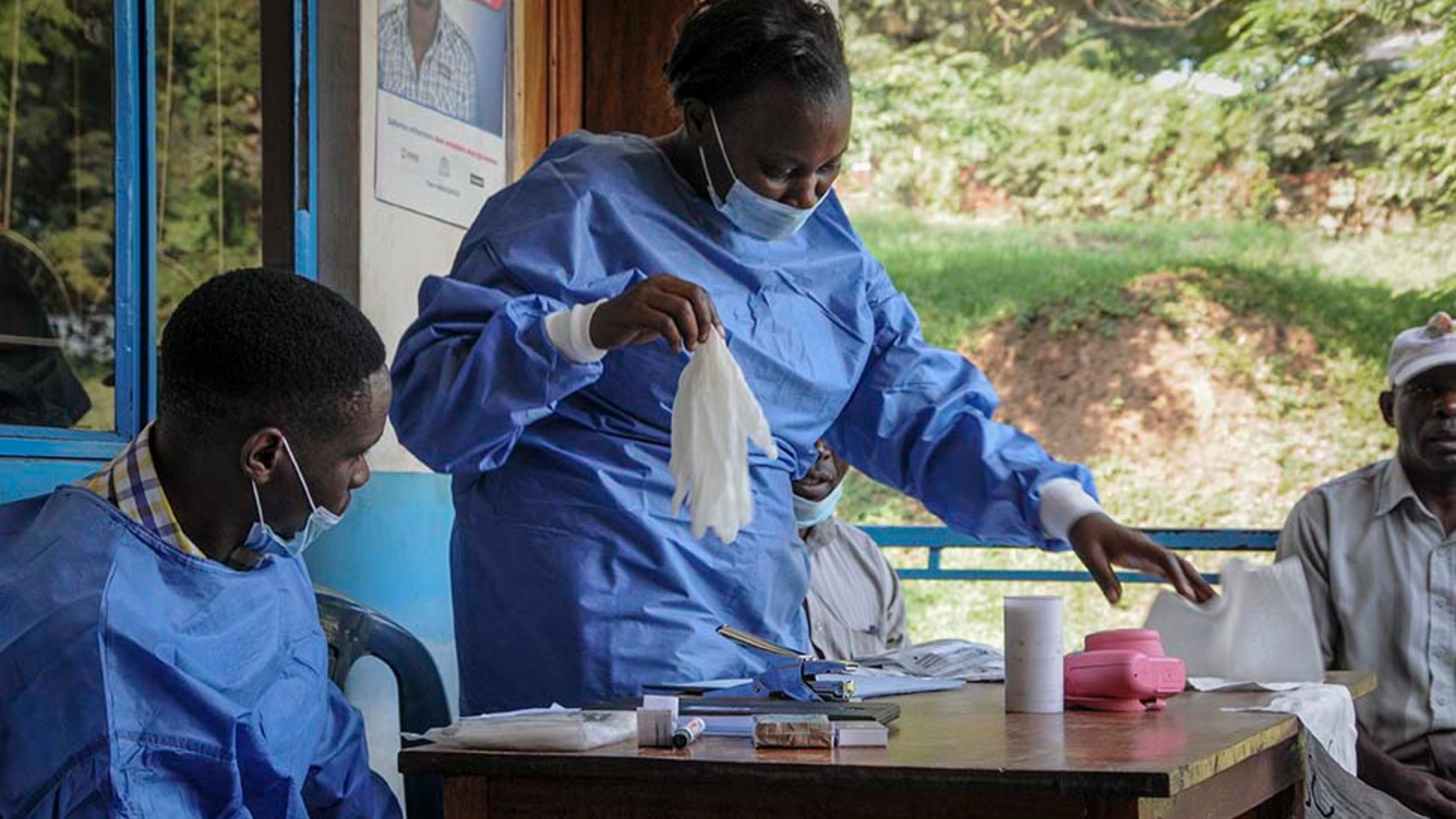 A health worker puts on protective clothing before vaccinating people against Ebola at the hospital in the village of Kagando, near the border with Congo, in June 2019. (AP Photo/Ronald Kabuubi)