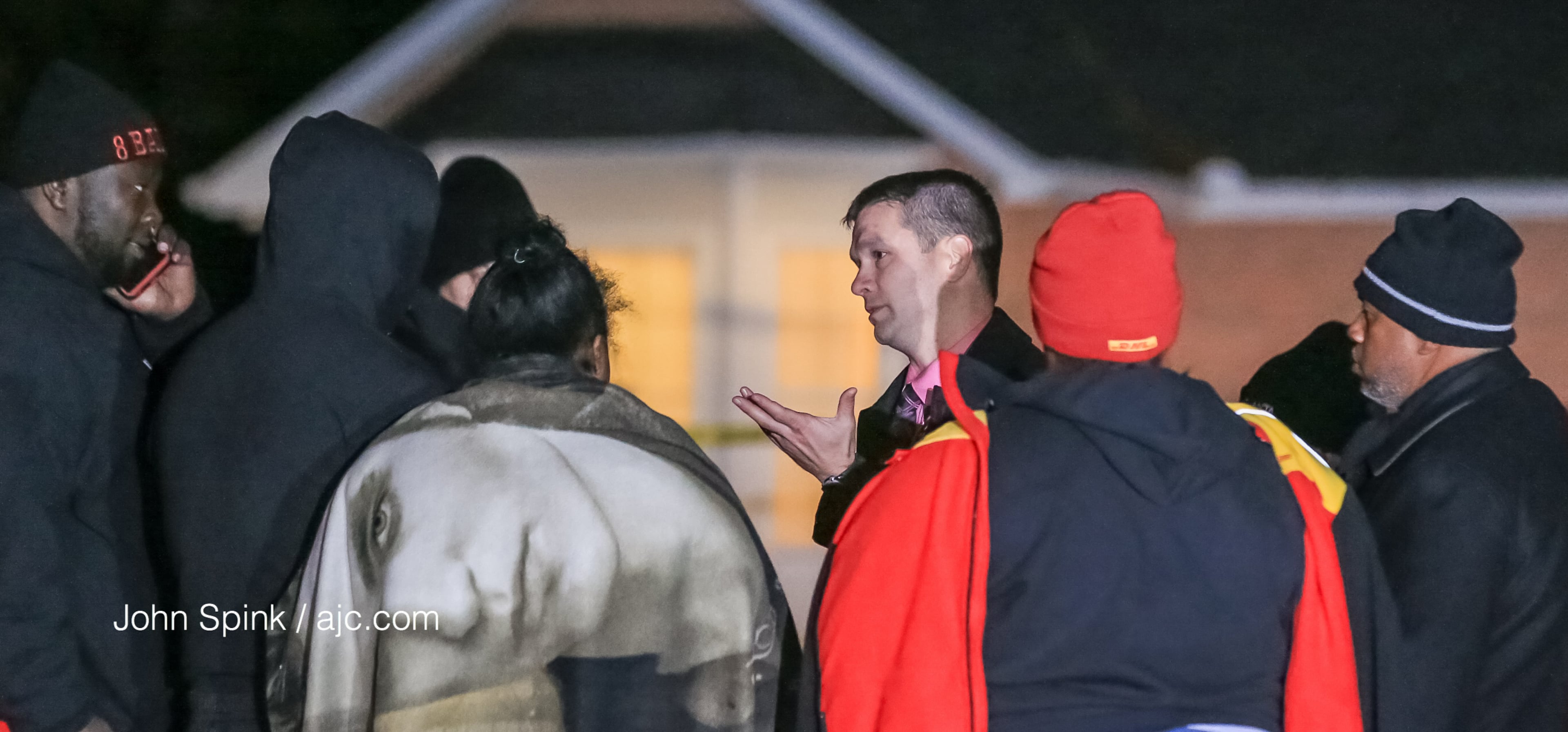 Atlanta police detectives speak with family members outside a home where two people were found dead. JOHN SPINK / JSPINK@AJC.COM