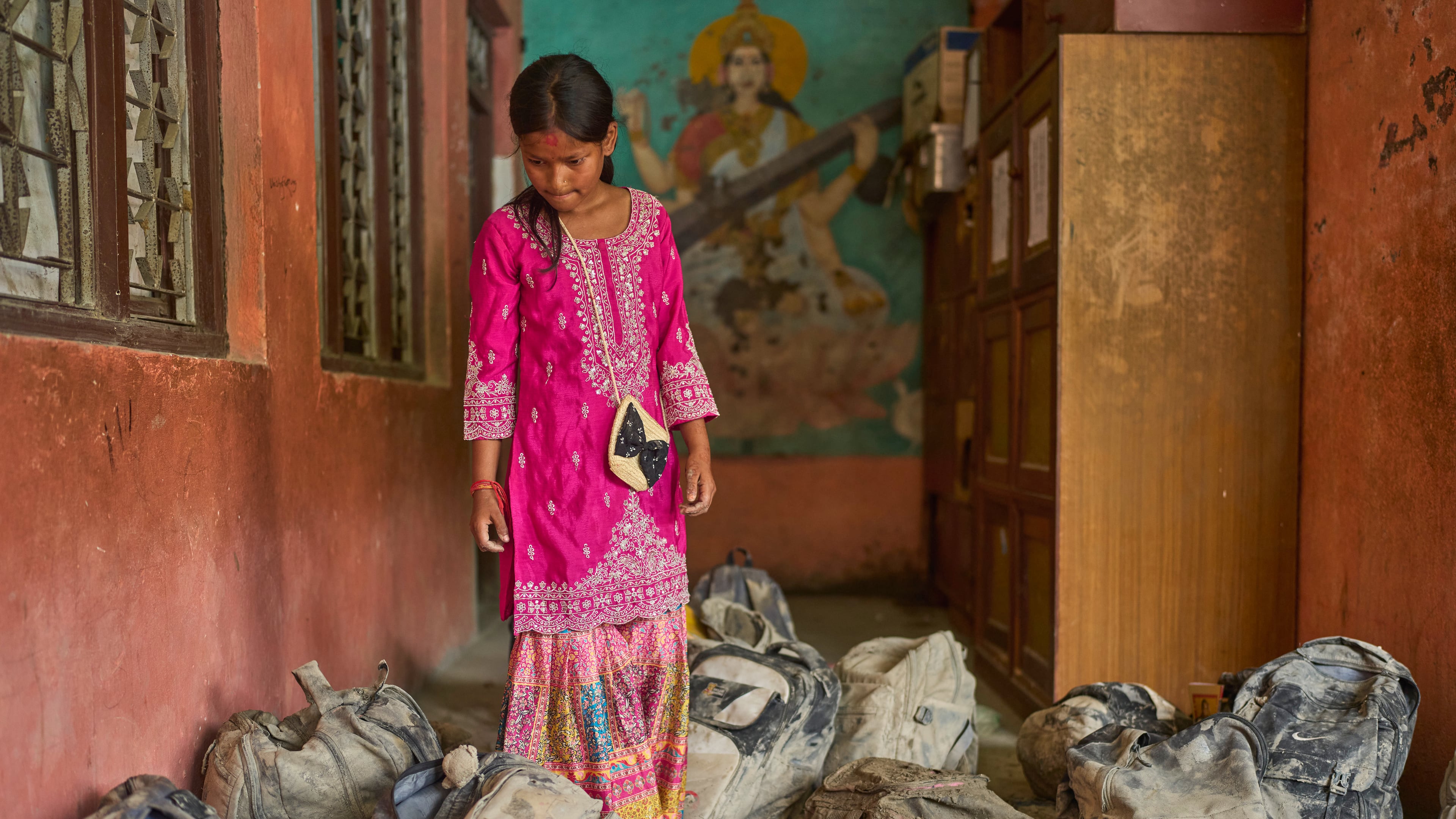 A student searches for her school bag from a pile extracted from the mud brought in by the recent flash floods, at the Shree Bagheswori Madhyamik School in Galchhi, Dhading district of Nepal Sunday, Aug. 30, 2026. (AP Photo/Niranjan Shrestha)