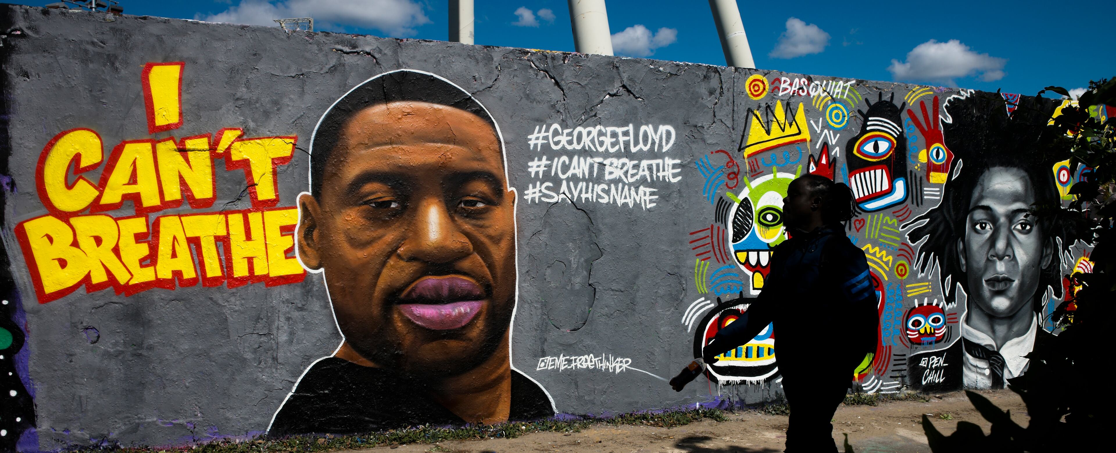 A man walk in front of a graffiti by artist 'EME Freethinker' that depict George Floyd is painted on a wall in the public park Mauerpark in Berlin, Germany, Saturday, May 30, 2020. Floyd died after being restrained by Minneapolis police officers on Memorial Day, May 25, in the United States. (AP Photo/Markus Schreiber)