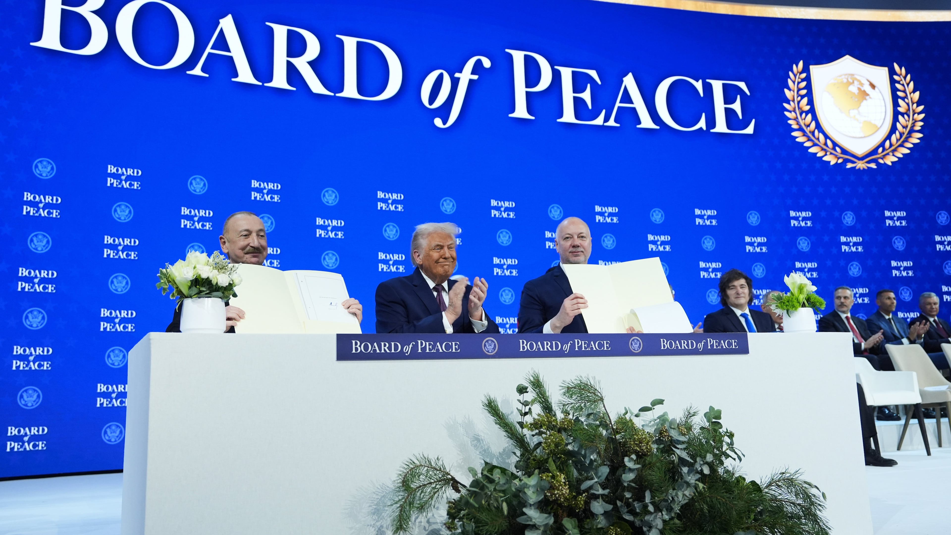 FILE - President Donald Trump, center, applauds as Ilham Aliyev, President of Azerbaijan, left, and Bulgaria's Prime Minister Rossen Jeliazkov, right, hold up their signed Board of Peace charter during the Annual Meeting of the World Economic Forum in Davos, Switzerland, Jan. 22, 2026. (AP Photo/Evan Vucci, File)