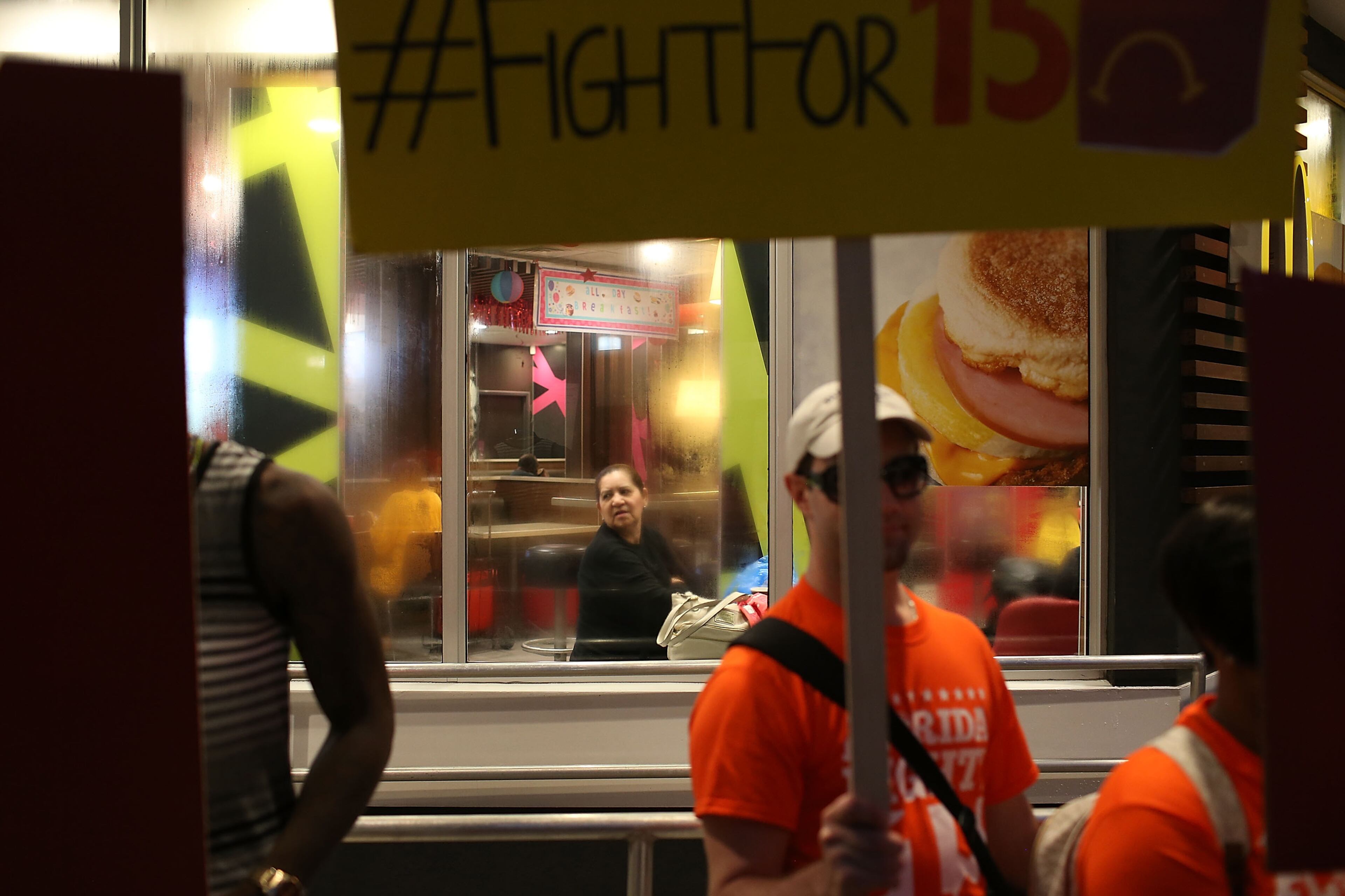 MIAMI, FL - NOVEMBER 10: A customer looks out at workers protesting outside the McDonald's restaurant on November 10, 2015 in Miami, Florida. The protesters are demanding action from state legislators and presidential candidates to raise the minimum wage to $15 an hour. (Photo by Joe Raedle/Getty Images)
