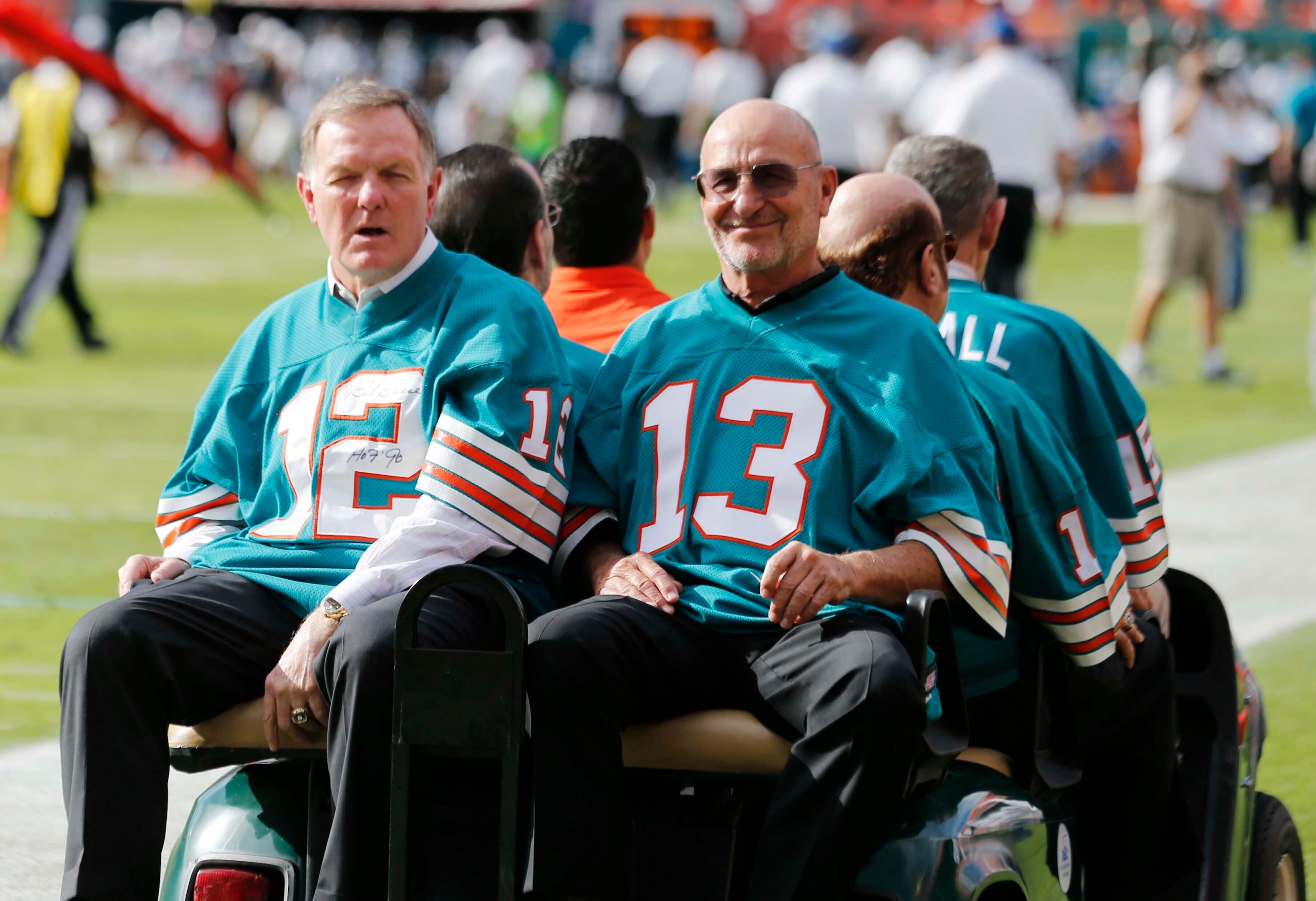 In this Dec. 16, 2012 file photo, Jake Scott (13) and Bob Griese (12) are driven onto the field for a halftime celebration of the 1972 Miami Dolphins. (AP Photo/John Bazemore, File)