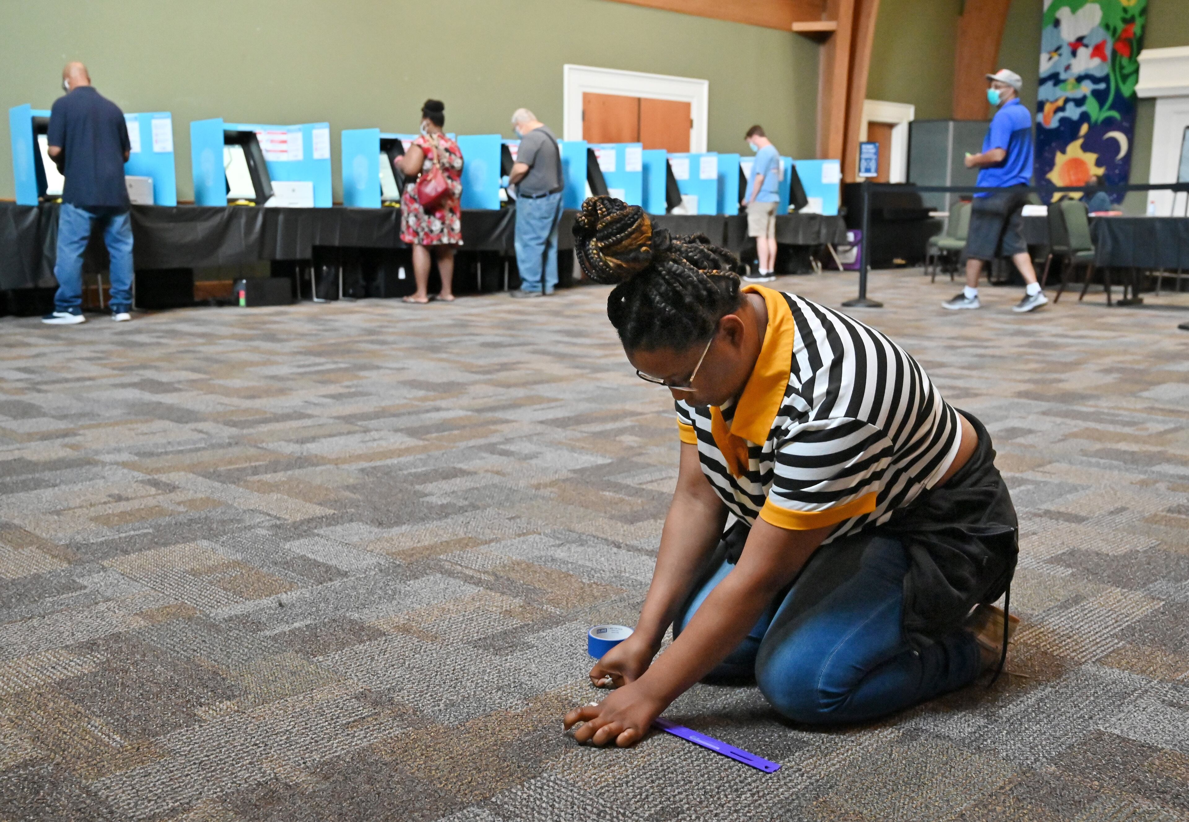 June 9, 2020 Duluth - Kasharri Blacknell, poll worker, places tape indicators for maintaining social distancing as Gwinnett County residents cast their votes during the Georgia primary elections at Pleasant Hill Presbyterian Church in Duluth on Tuesday, June 9, 2020. (Hyosub Shin / Hyosub.Shin@ajc.com)