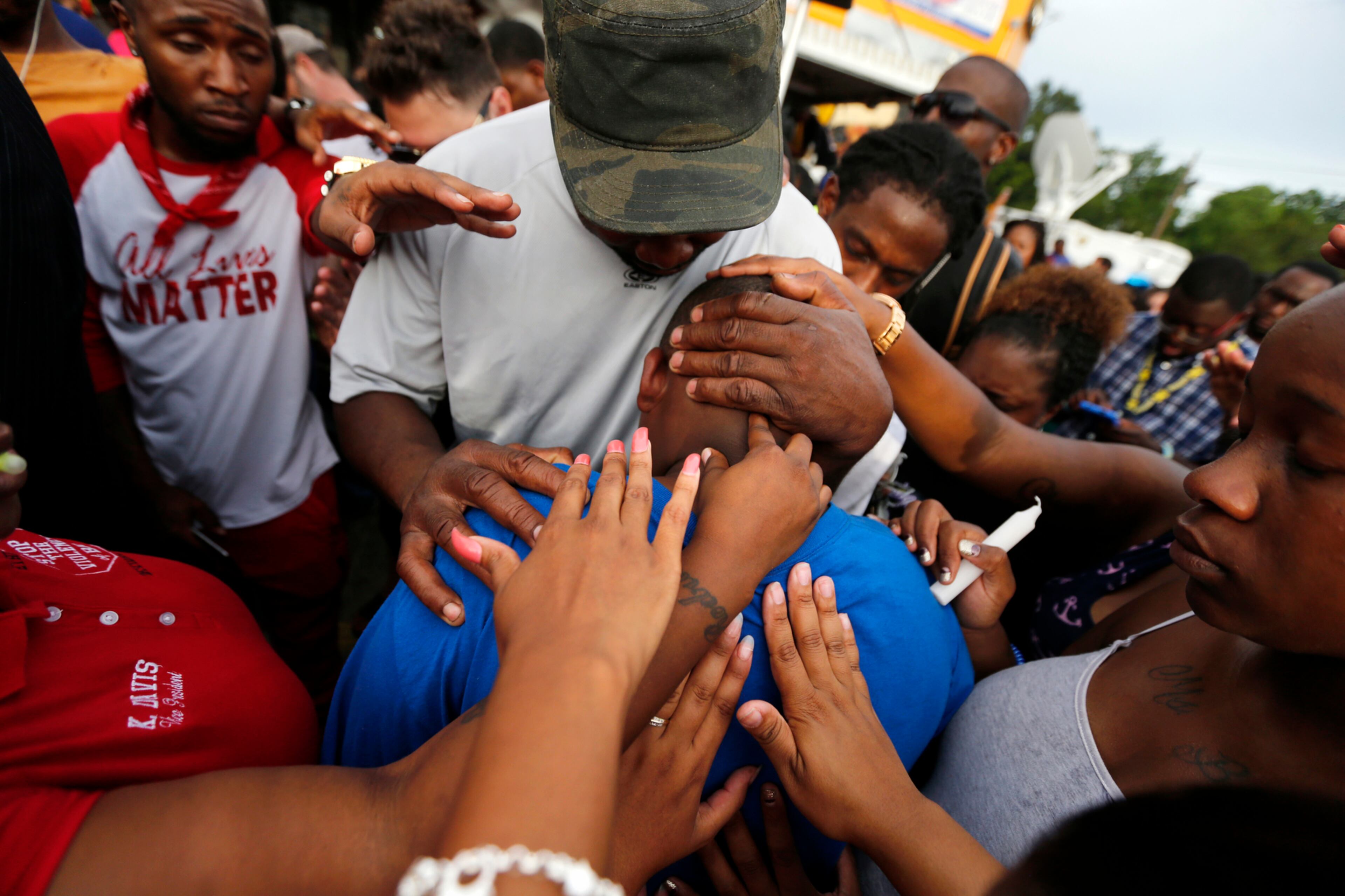 COMFORT FOR A SON--Cameron Sterling, son of Alton Sterling, is comforted by hands from the crowd at a vigil outside the Triple S convenience store in Baton Rouge, La., Wednesday, July 6, 2016. Alton Sterling, 37, was shot and killed by Baton Rouge police outside the store where he was selling CDs. (AP Photo/Gerald Herbert)