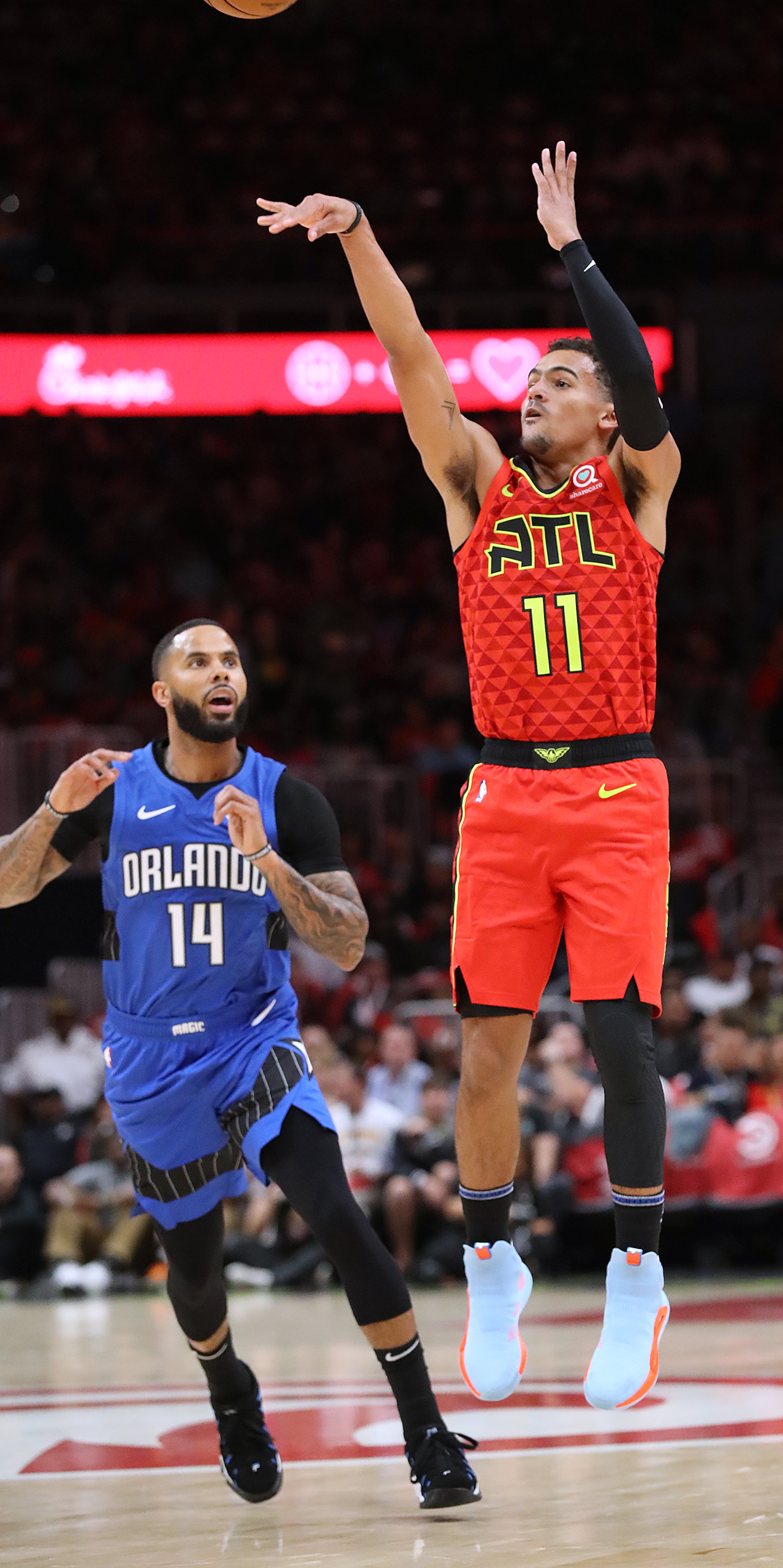 Hawks guard Trae Young makes a three pointer past Orlando Magic guard D.J. Augustin during the first half in the home opener in a NBA basketball game on Saturday, October 26, 2019, in Atlanta. Curtis Compton/ccompton@ajc.com
