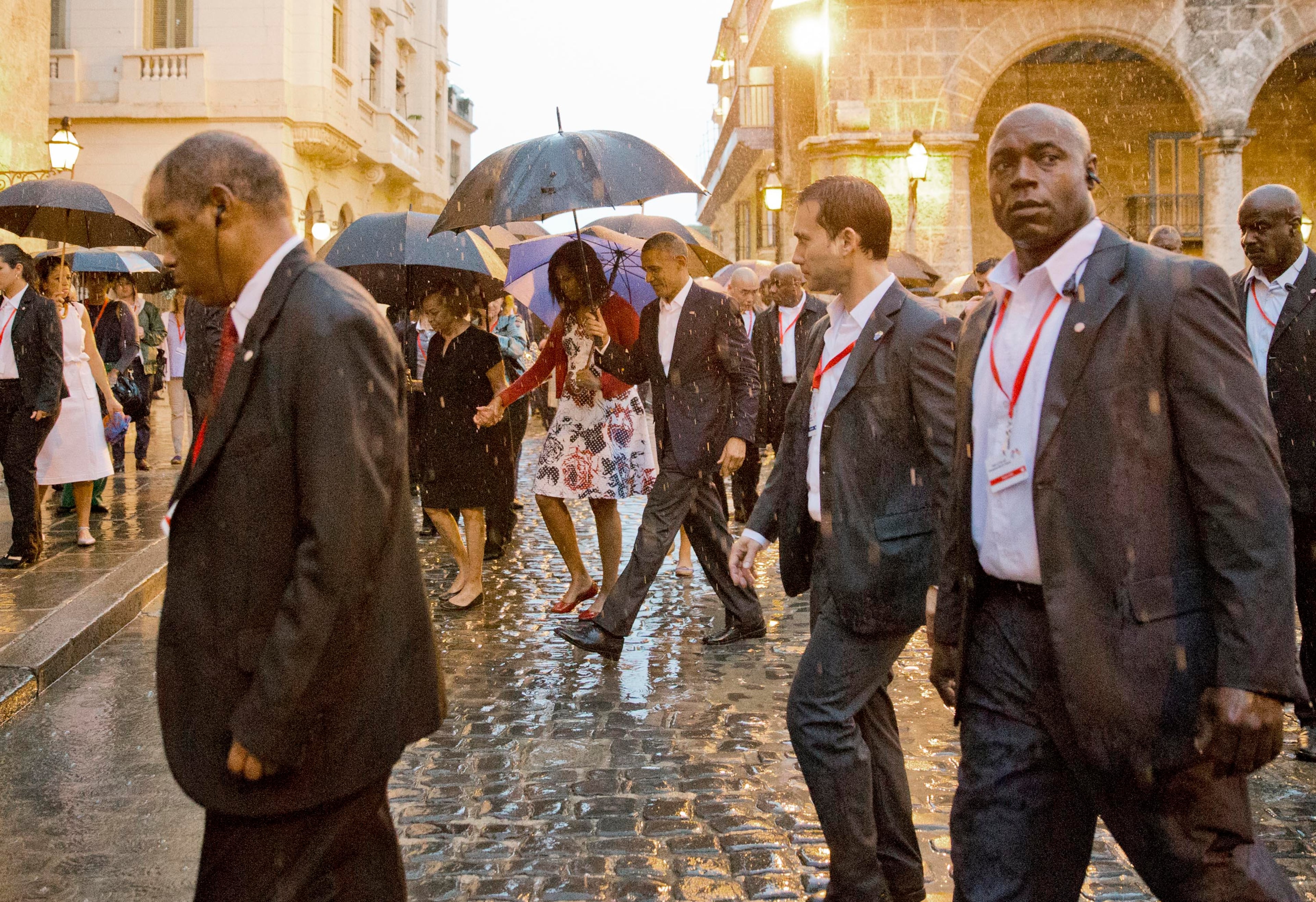 U.S. President Barack Obama, center, walks in the rain with first lady Michelle Obama, who is holding the arm of her mother Marian Robinson, during a walking tour of Old Havana, Cuba, on March 20, 2016. Obama became the first U.S. president to visit the island in nearly 90 years.
