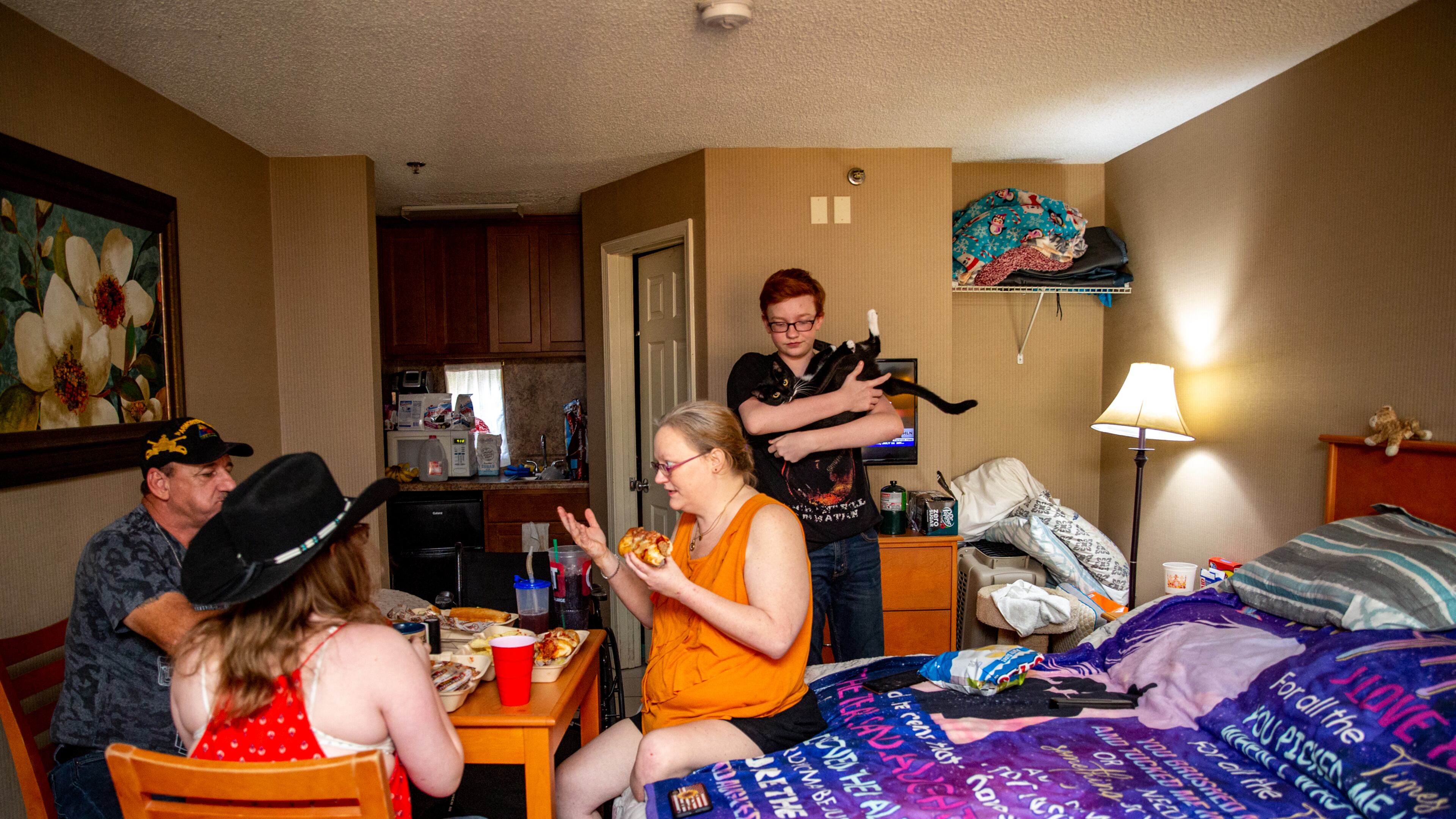The Perdue family -- David, his wife Crystal, son Zachary, 15, and daughter Evangelene, 12, have dinner Friday, June 25, 2021 in their room at the Whits Inn, an extended stay hotel in Loganville where they live with Felix the cat and two ferrets. (Jenni Girtman for The Atlanta Journal-Constitution)