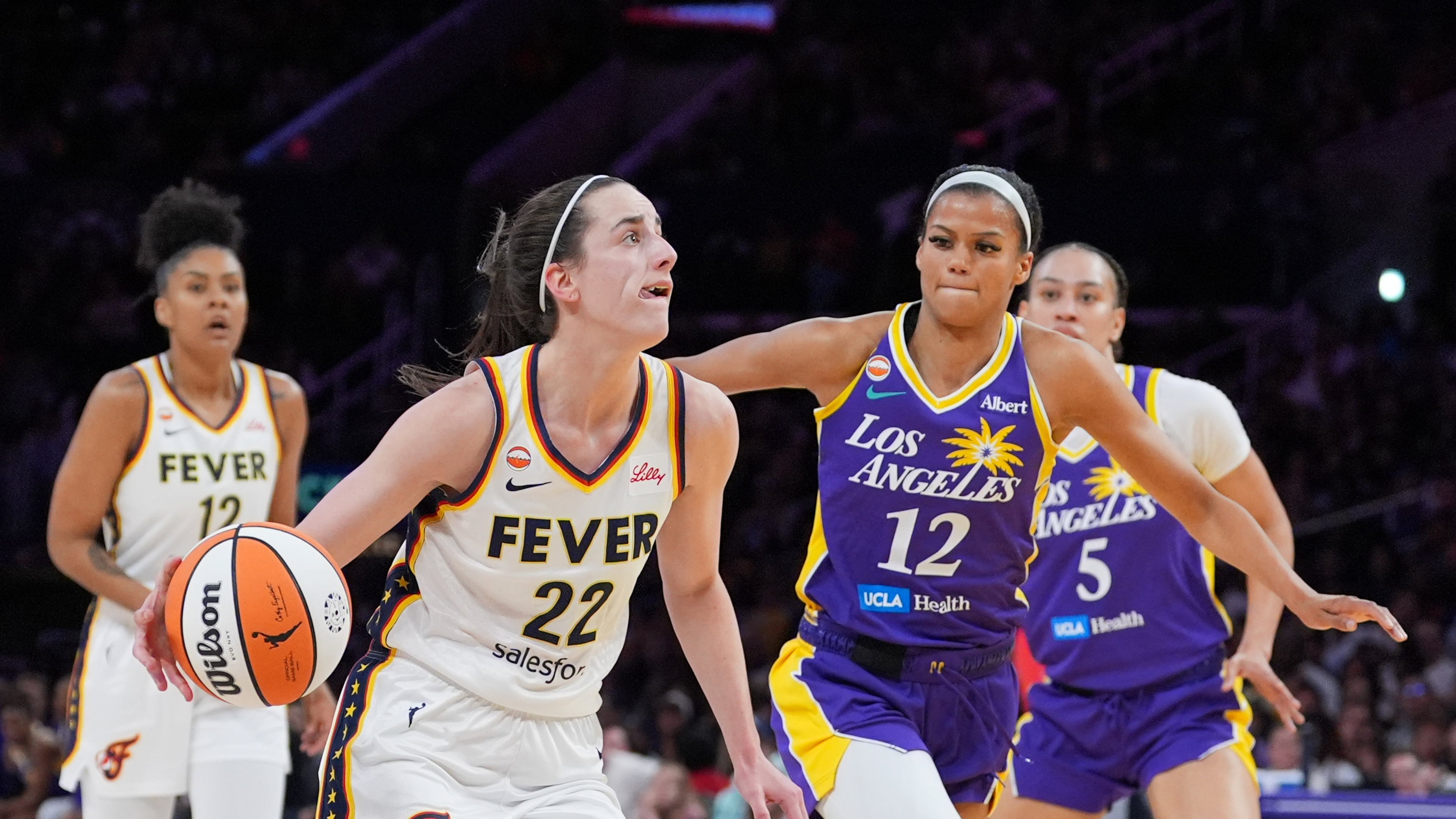 Indiana Fever guard Caitlin Clark (22) drives past Los Angeles Sparks guard-forward Rae Burrell (12) during the first half of a WNBA basketball game Wednesday, May 13, 2026, in Los Angeles. (AP Photo/Jae C. Hong)