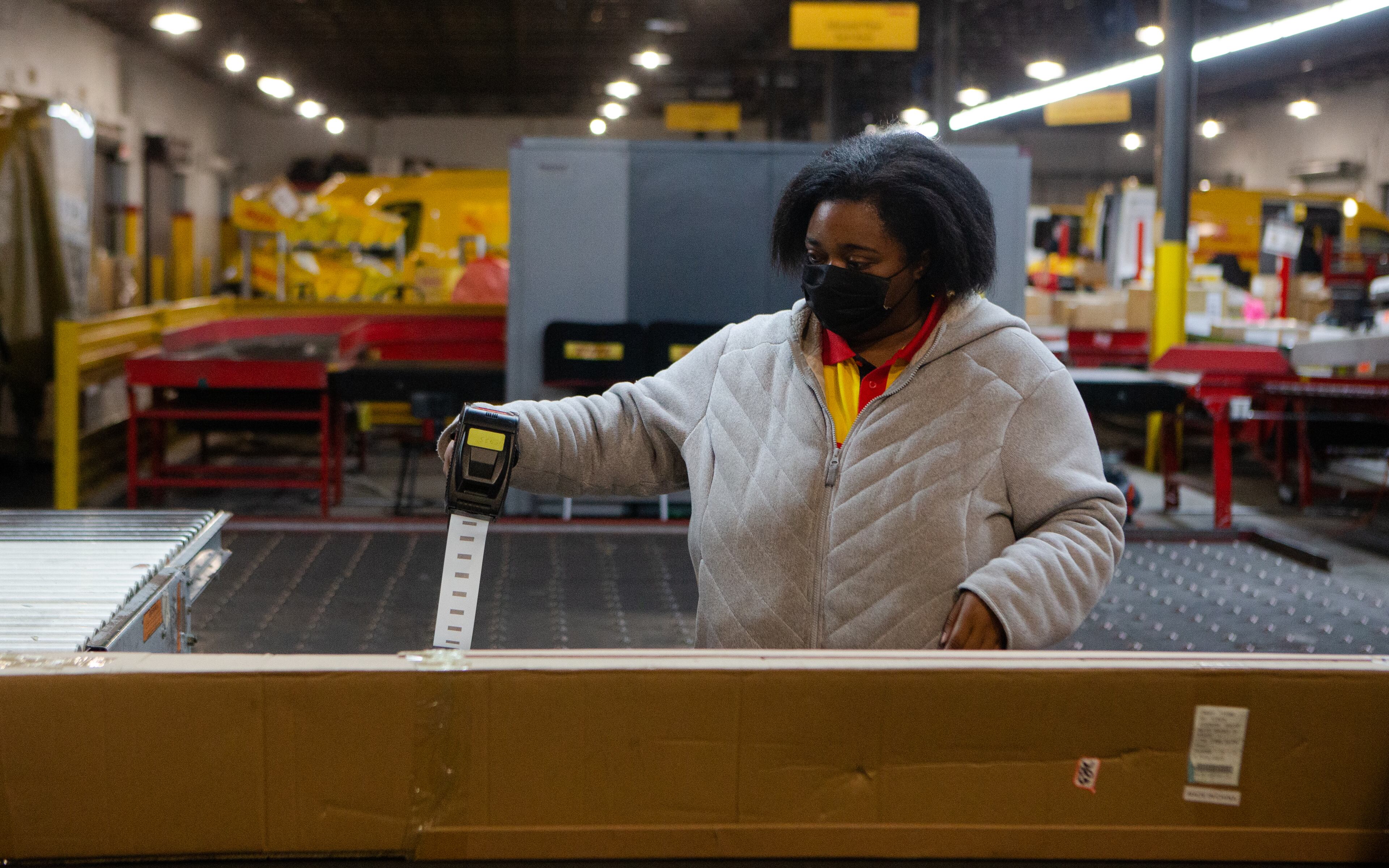 Natasha Garrett labels packages on Wednesday, December 16, 2020, at DHL Express in Atlanta. Workers at the shipping center worked to fulfill orders during the holiday rush. CHRISTINA MATACOTTA FOR THE ATLANTA JOURNAL-CONSTITUTION.