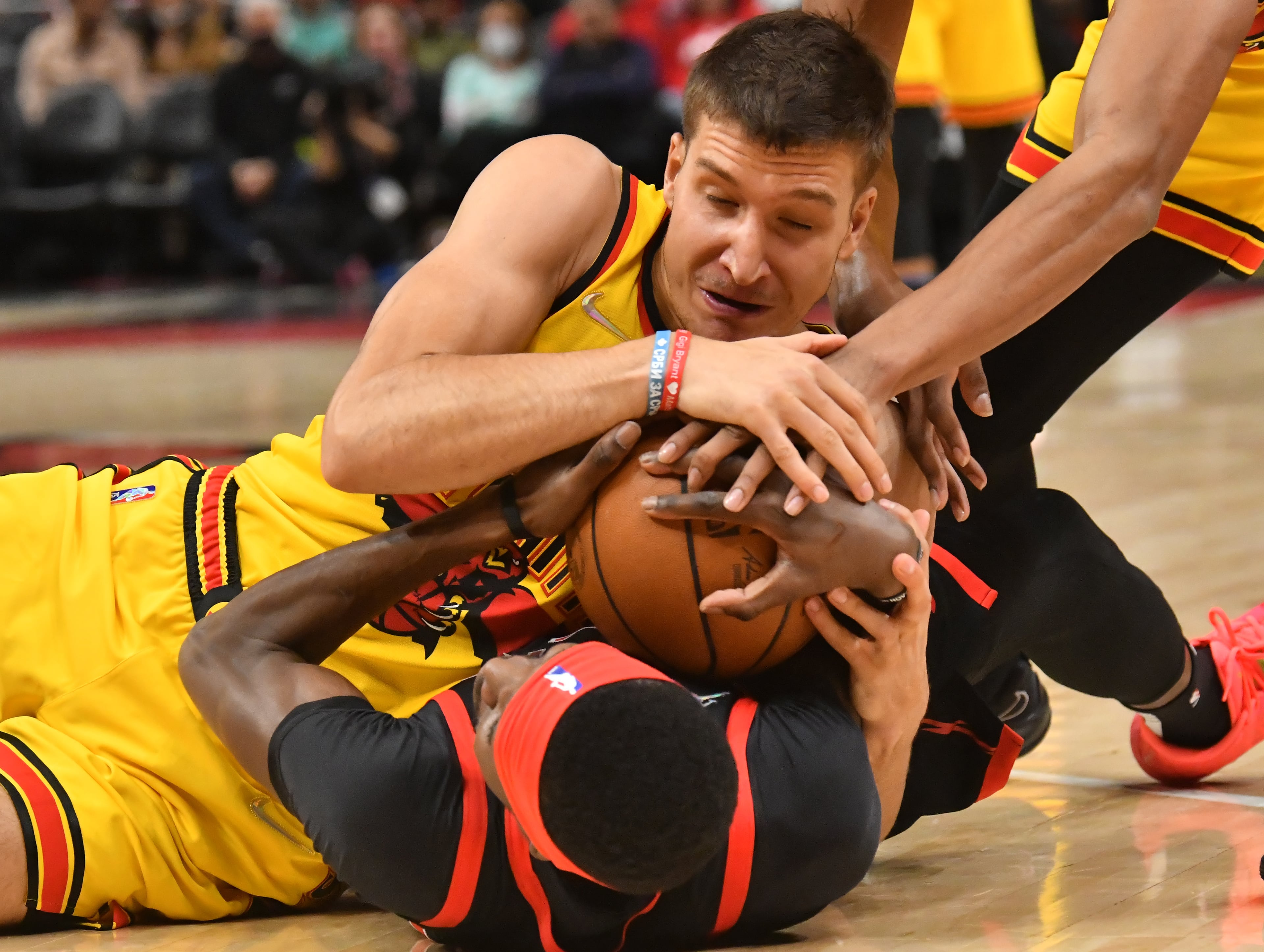 Atlanta Hawks guard Bogdan Bogdanovic (13) and Toronto Raptors forward Chris Boucher (25) fight for a loose ball during the first half at State Farm Arena on Saturday, February 26, 2022. The Hawks won 127-100. (Hyosub Shin / Hyosub.Shin@ajc.com)
