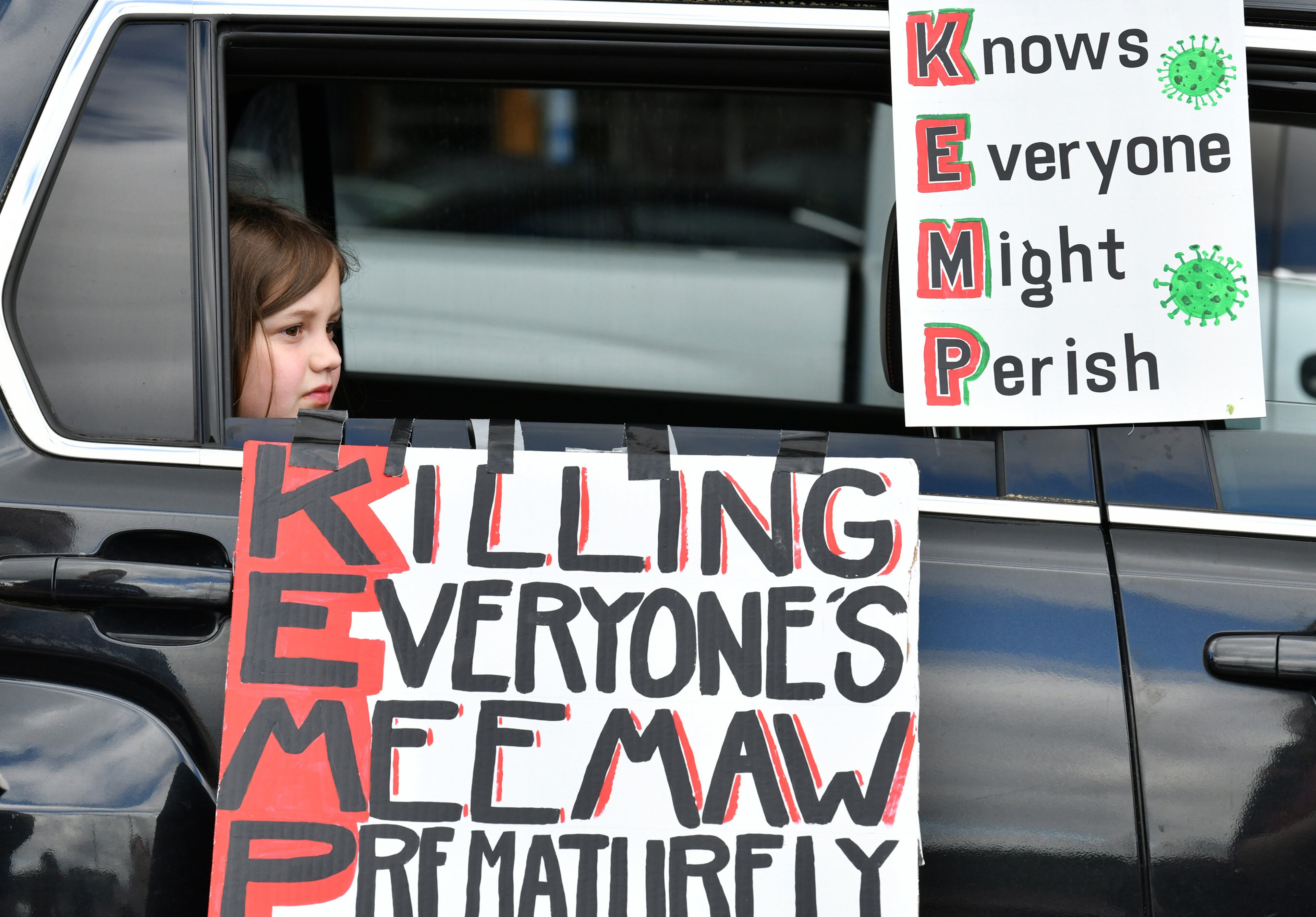 An 8-year-old watches her mother decorate her car before a drive-by protest against Gov. Kemp's decision to reopen some Georgia businesses on April 24, 2020. Over the next 30 days, the number of COVID-19 deaths in Georgia would more than double. (Hyosub Shin / Hyosub.Shin@ajc.com)