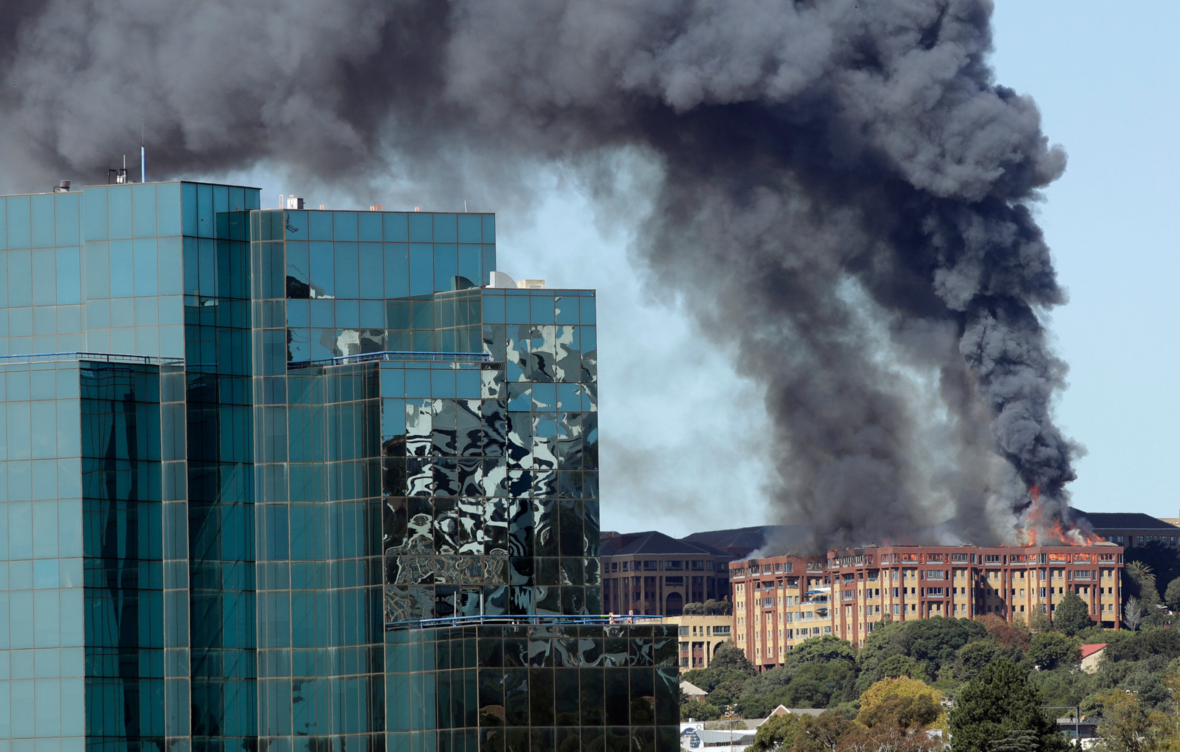 A pall of smoke drifts skyward as flames engulf the top floor of an office building in Johannesburg, South Africa, Tuesday, April 18, 2017, before being bought under control. All people were successfully evacuated from the building and no injuries were reported.(AP Photo/Themba Hadebe)