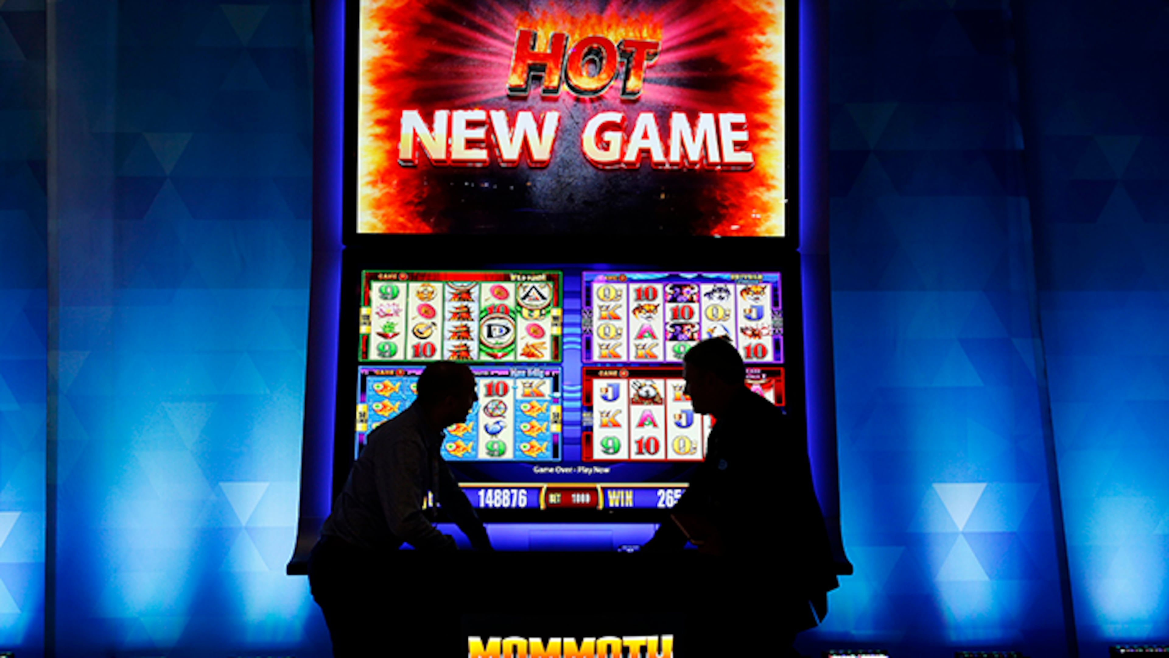 People stand in front of an oversized slot machine at the Aristocrat booth during the Global Gaming Expo, Wednesday, Sept. 30, 2015, in Las Vegas.