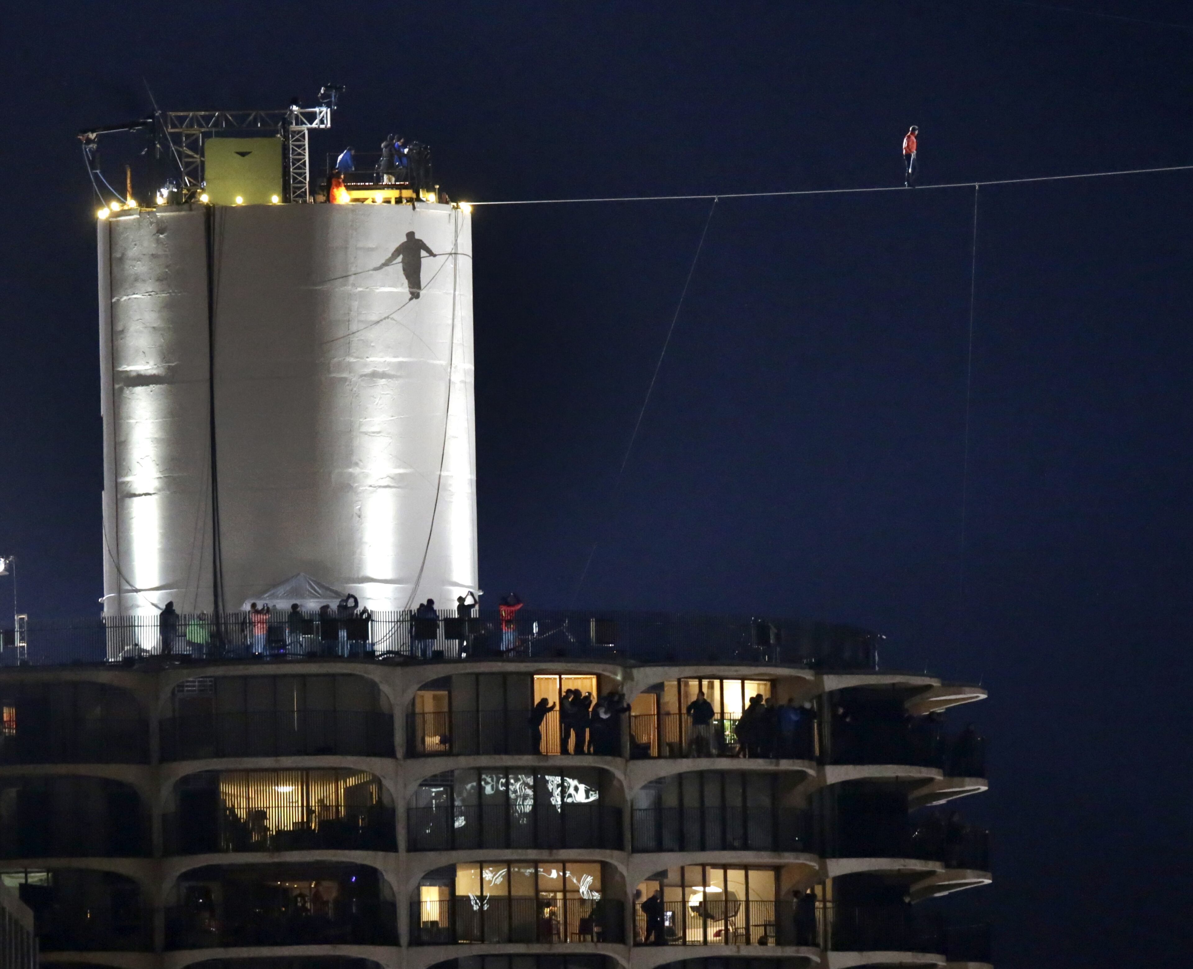The shadow of daredevil Nik Wallenda is cast against the West Marina Tower as he begins his tightrope walk uphill at a 15-degree angle, from the Marina City west tower across the Chicago River to the top of the Leo Burnett Building Sunday, Nov. 2, 2014, in Chicago. (AP Photo/Charles Rex Arbogast)