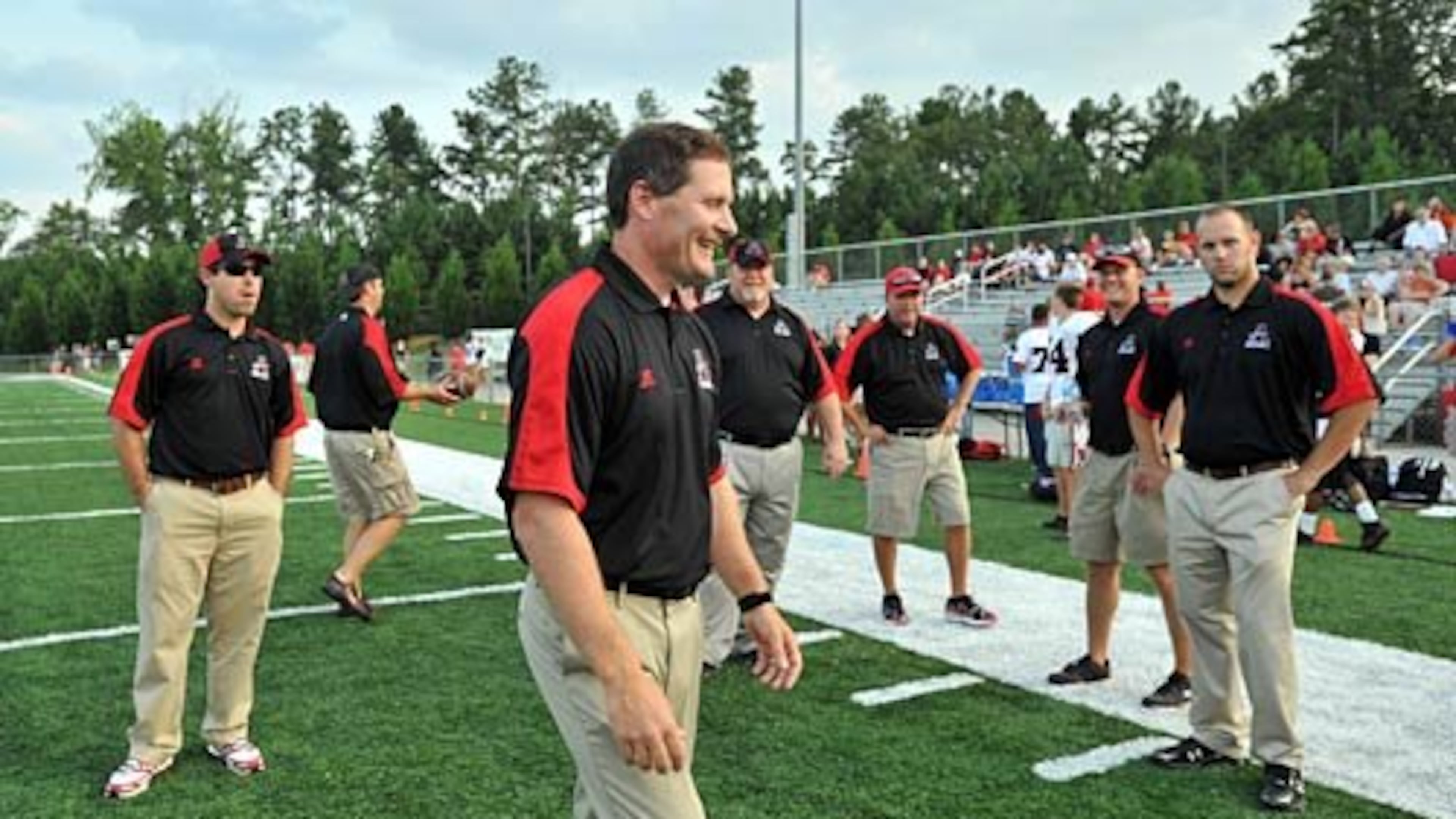 Allatoona head coach Gary Varner (foreground) smiles as he talks with his staff prior to the game. When Cobb County went through budget woes, the entire Allatoona High coaching staff was initially dismissed.