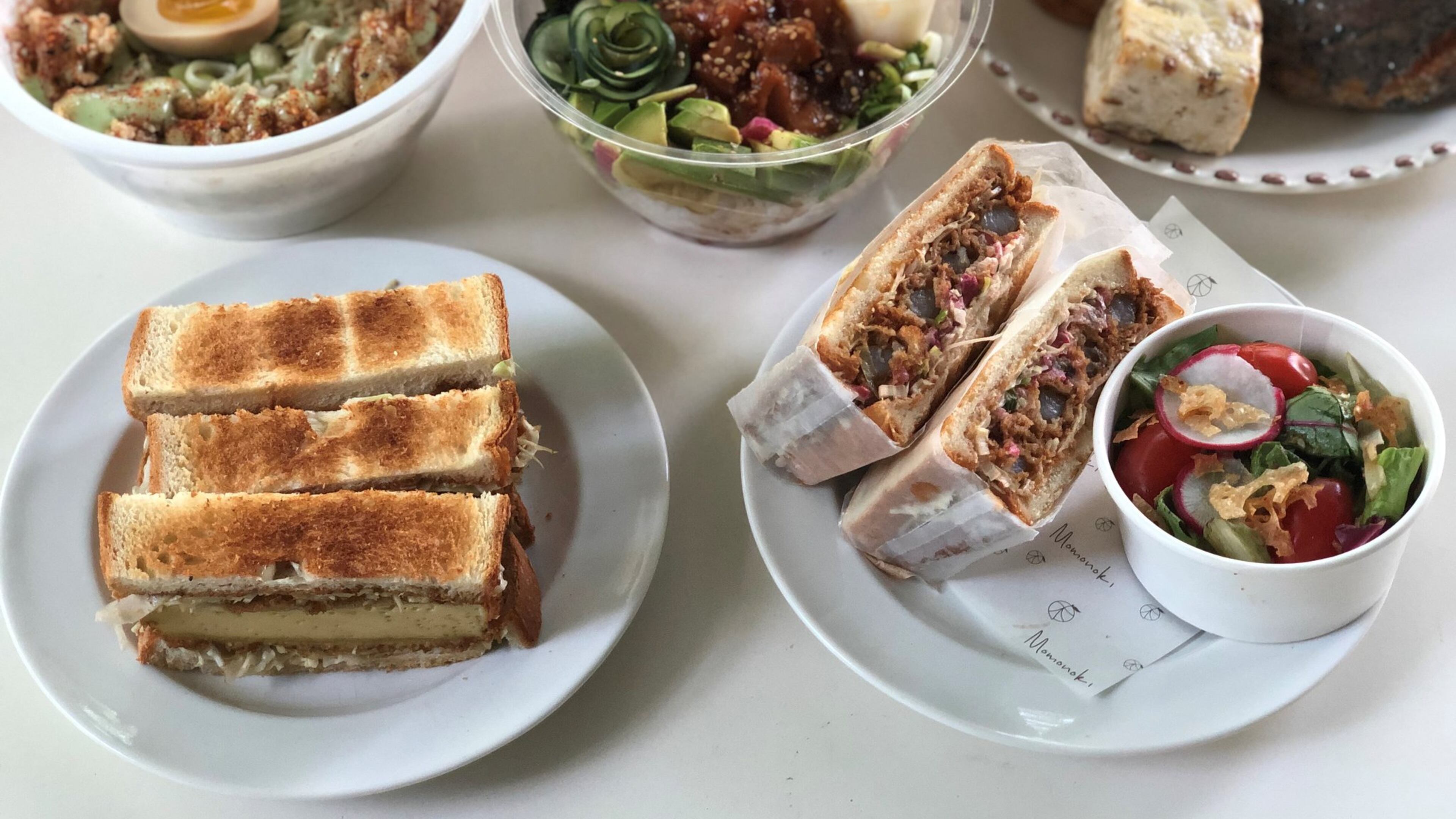 Takeout items from Momonoki include (clockwise from upper left): chicken karaage bowl, poke bowl, a pastry assortment, shrimp katsu sando and egg custard sando. CONTRIBUTED BY WENDELL BROCK