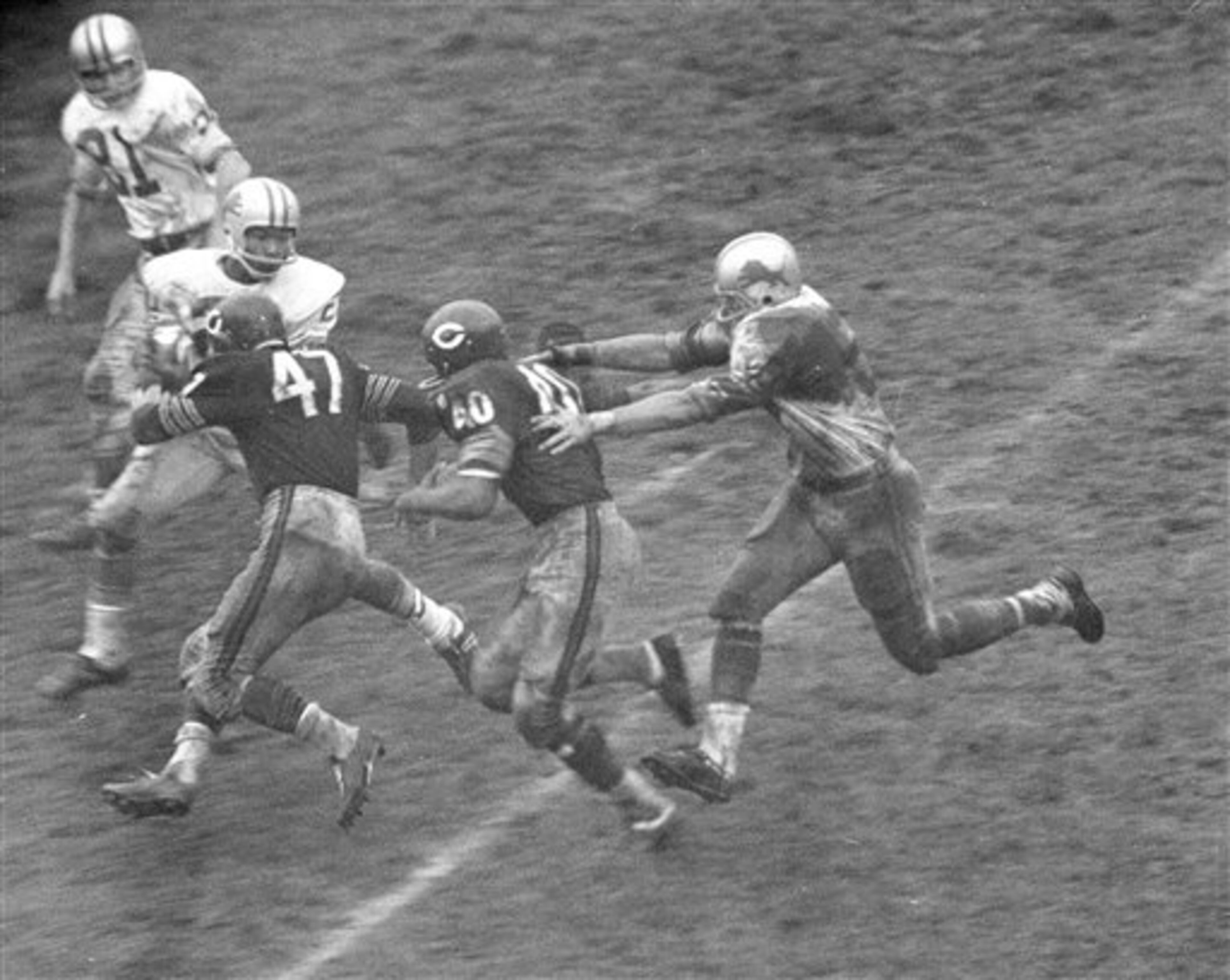 An unidentified Detroit Lion defender is about to grab Bears Gale Sayers after Sayers moved through the line for a good gain in the second period of game in Chicago, Oct. 15, 1967. Leading Sayers is blocker Johnny Morris. Detroit defender in front of Morris is not identified. (AP Photo/Larry Stoddard)
