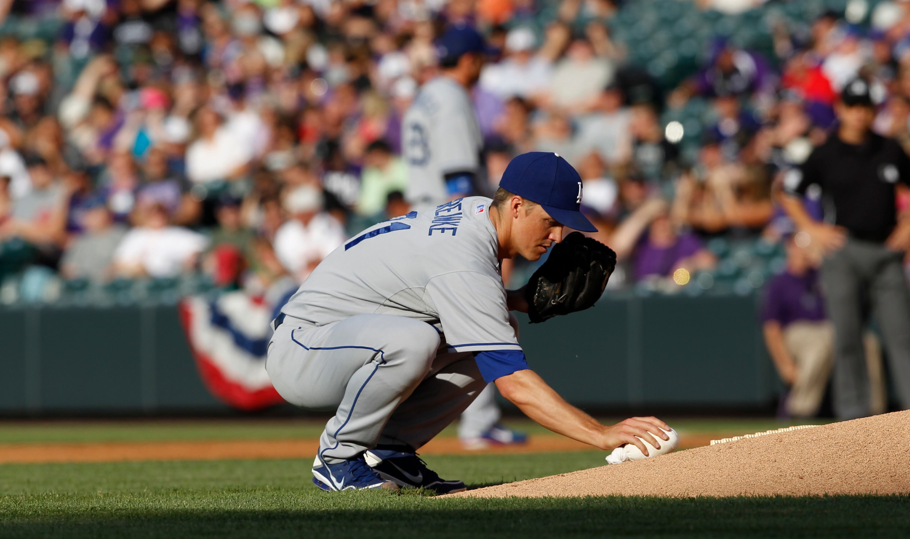 Los Angeles Dodgers starting pitcher Zack Greinke places the resin bag before facing the Colorado Rockies in the first inning of a baseball game in Denver on Wednesday, July 3, 2013. (AP Photo/David Zalubowski)