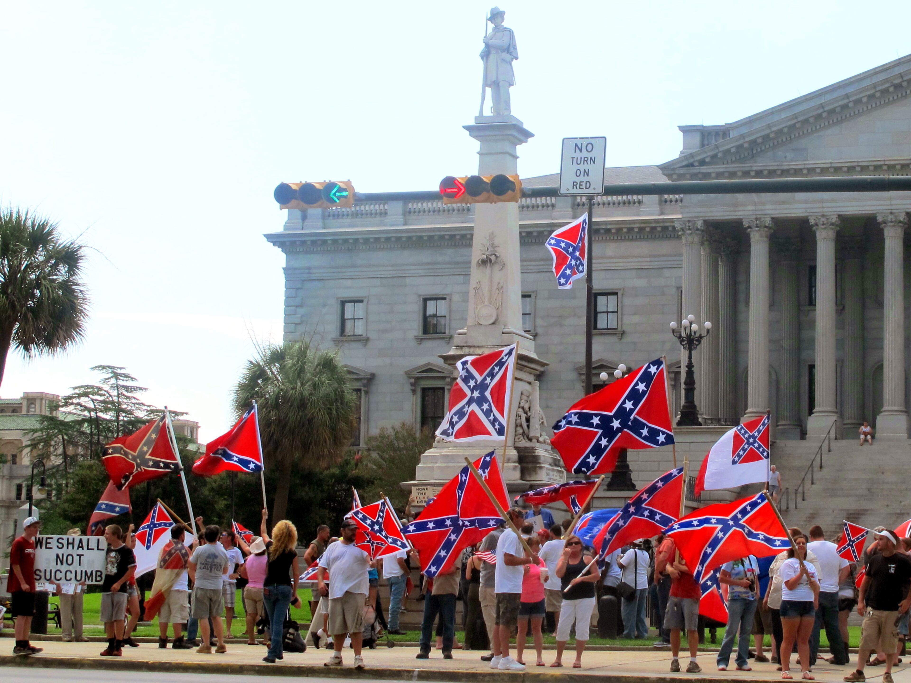 Supporters of keeping the Confederate battle flag flying at a Confederate monument at the South Carolina Statehouse wave flags during a rally in front of the statehouse in Columbia, S.C., on Saturday, June 27, 2015. Gov. Nikki Haley and a number of other state leaders have called for the removal of the flag following the shooting deaths of nine black parishioners in a church in Charleston. (AP Photo/Bruce Smith)