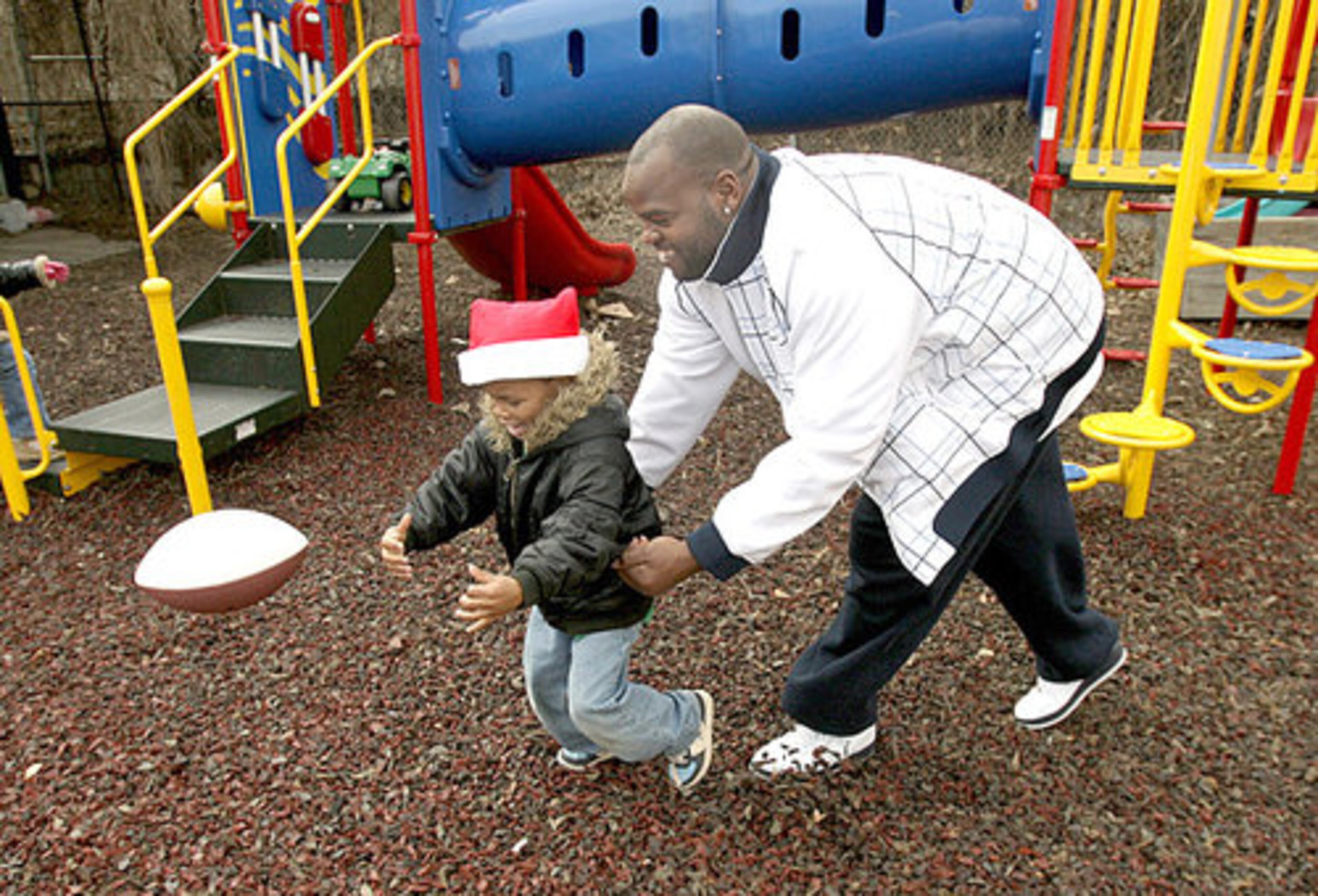 Moorehead aligns Daquon Henderson in place to catch a pass. The Falcons players played football and basketball with kids at the shelter. They also autographed some footballs.