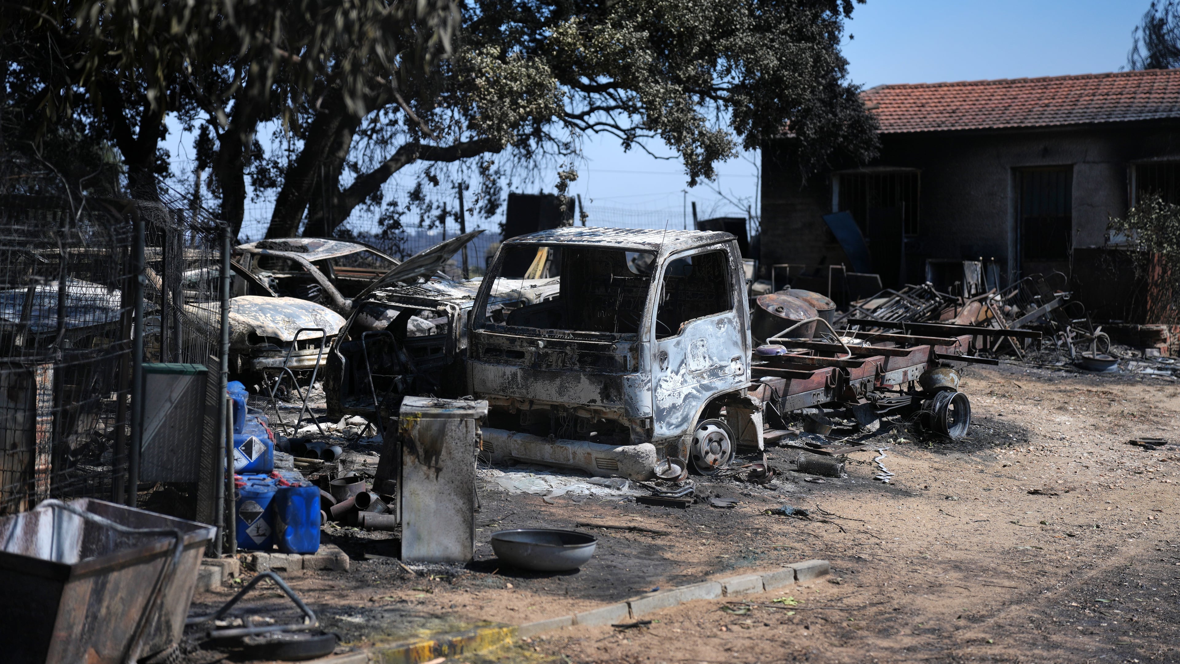 Burnt vehicles sit outside a charred house in Navas del Rey, west of Madrid, Spain, where wildfires have forced tens of thousands to be evacuated, Sunday, July 26, 2026. (AP Photo/Manu Fernandez)