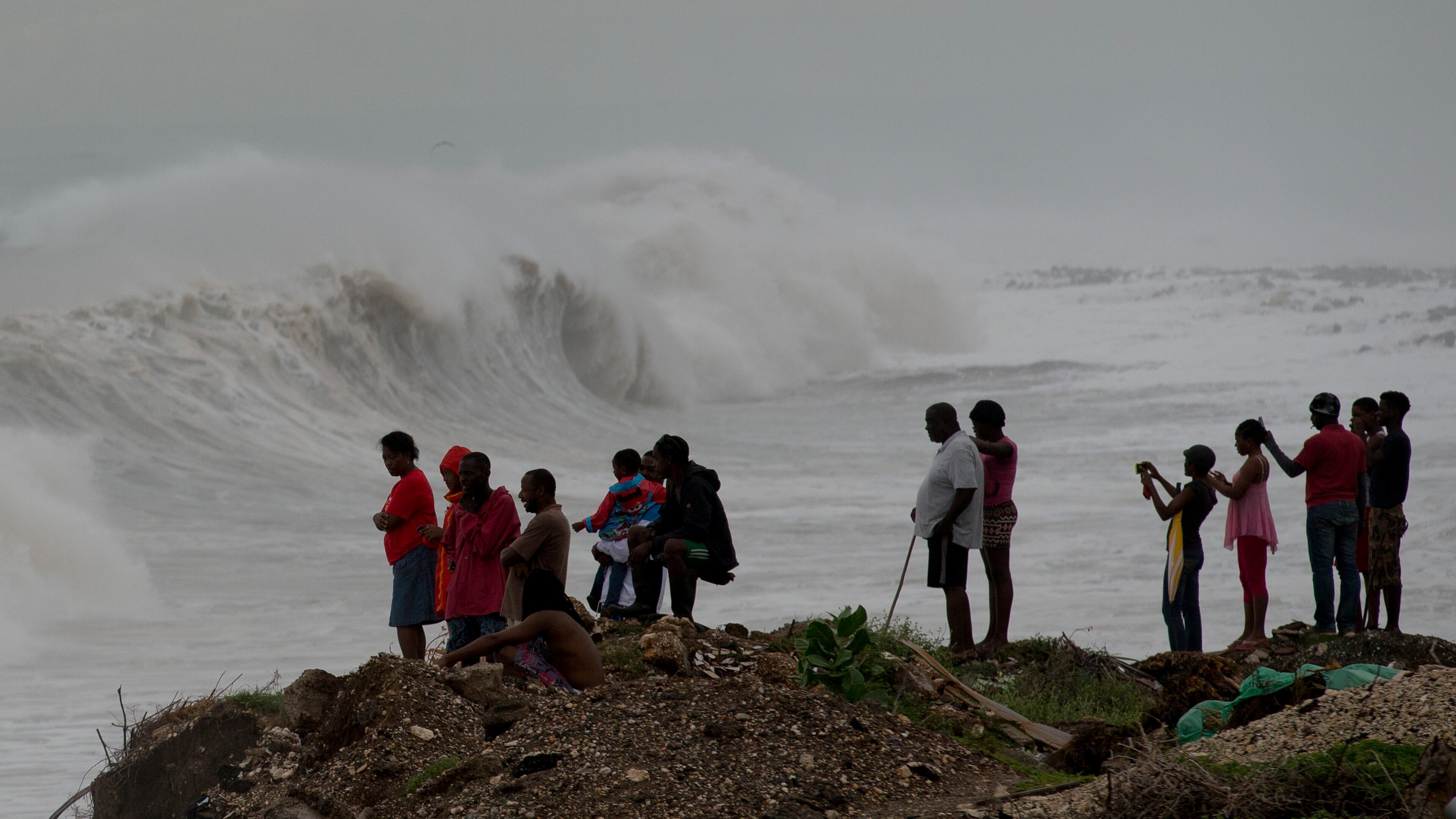People stand on the coast watching the surf produced by Hurricane Matthew, on the outskirts of Kingston, Jamaica, Monday, Oct. 3, 2016. A hurricane warning is in effect for Jamaica, Haiti, and the Cuban provinces of Guantanamo, Santiago de Cuba, Holguin, Granma and Las Tunas - as well as the southeastern Bahamas. (AP Photo/Eduardo Verdugo)