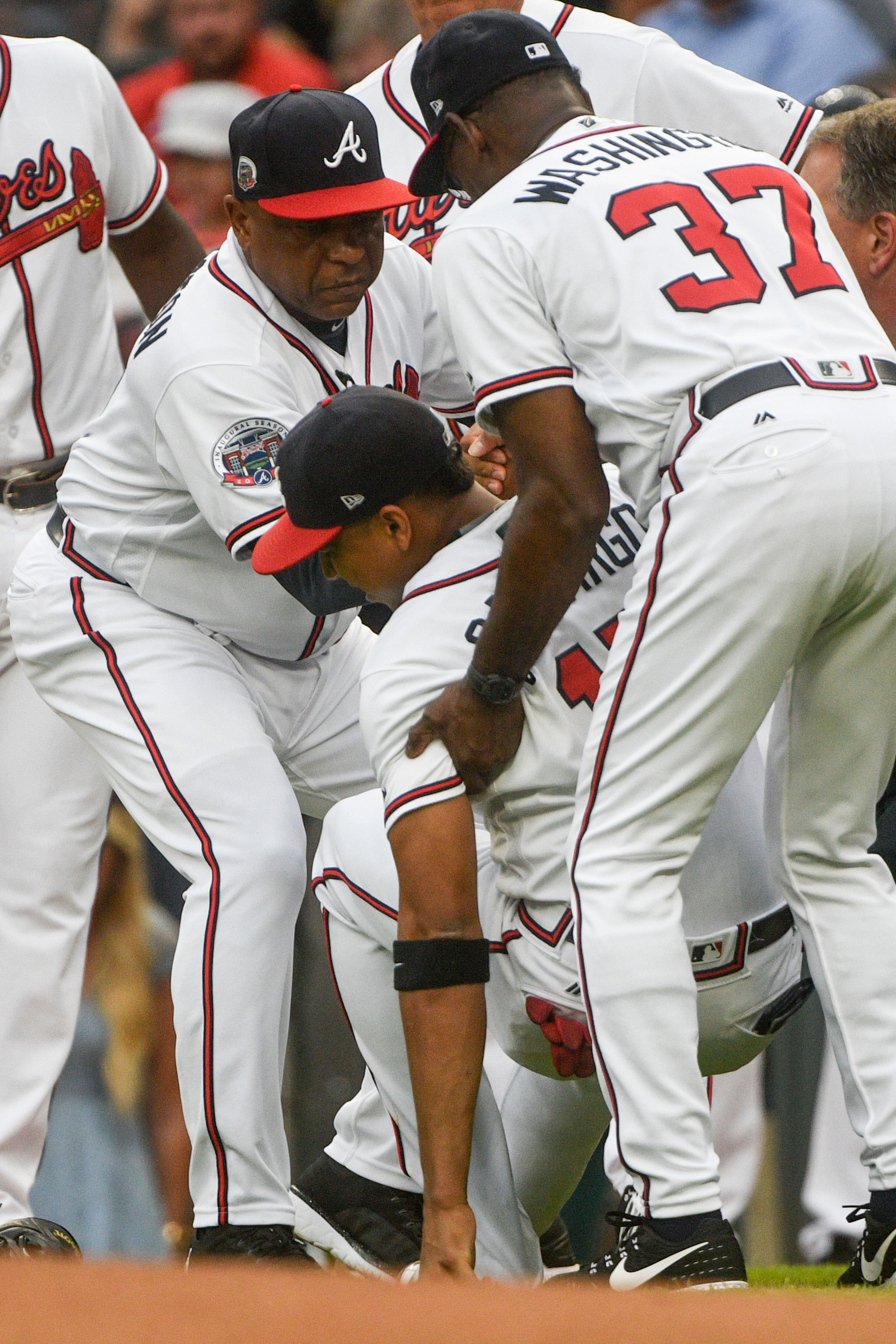 Atlanta Braves shortstop Johan Camargo is helped up by third base coach Ron Washington (37) and bench coach Terry Pendleton, left, after collapsing as he took the field before a baseball game against the Philadelphia Phillies, Tuesday, Aug. 8, 2017, in Atlanta. Jace Peterson took his place to start the game at shortstop. (AP Photo/John Amis)
