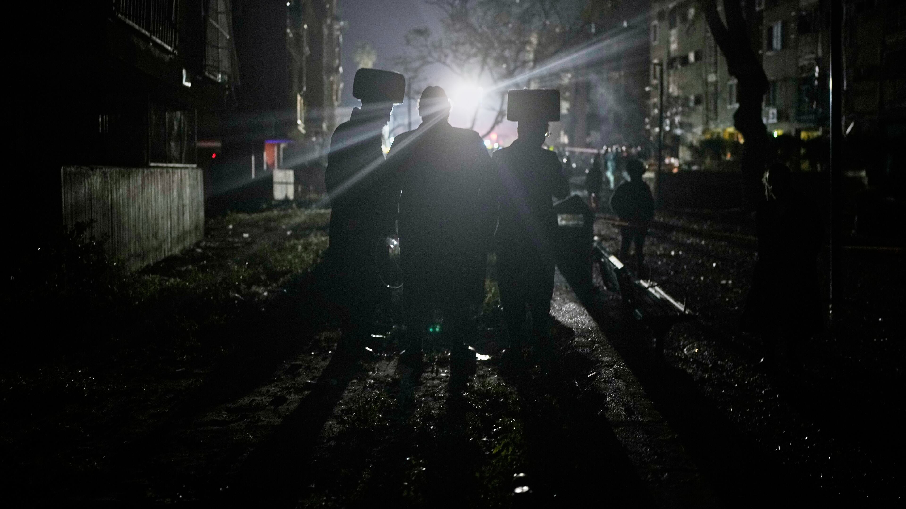 Ultra-Orthodox Jewish men watch as Israeli security forces and rescue teams operate at the site hit by an Iranian missile in Arad, southern Israel, Sunday, March 22, 2026. (AP Photo/Ohad Zwigenberg)
