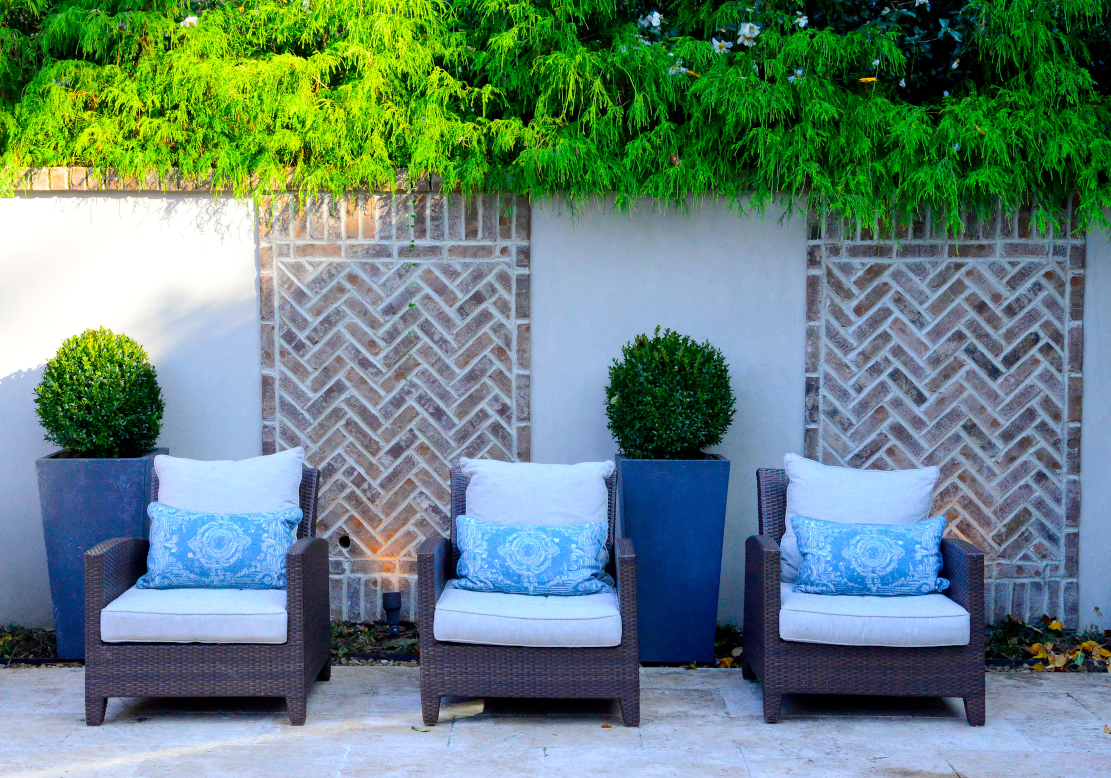 Brick in a herringbone pattern on the walls in the pool area matches the front of the home. The pattern adds visual interest and texture to the outdoors.