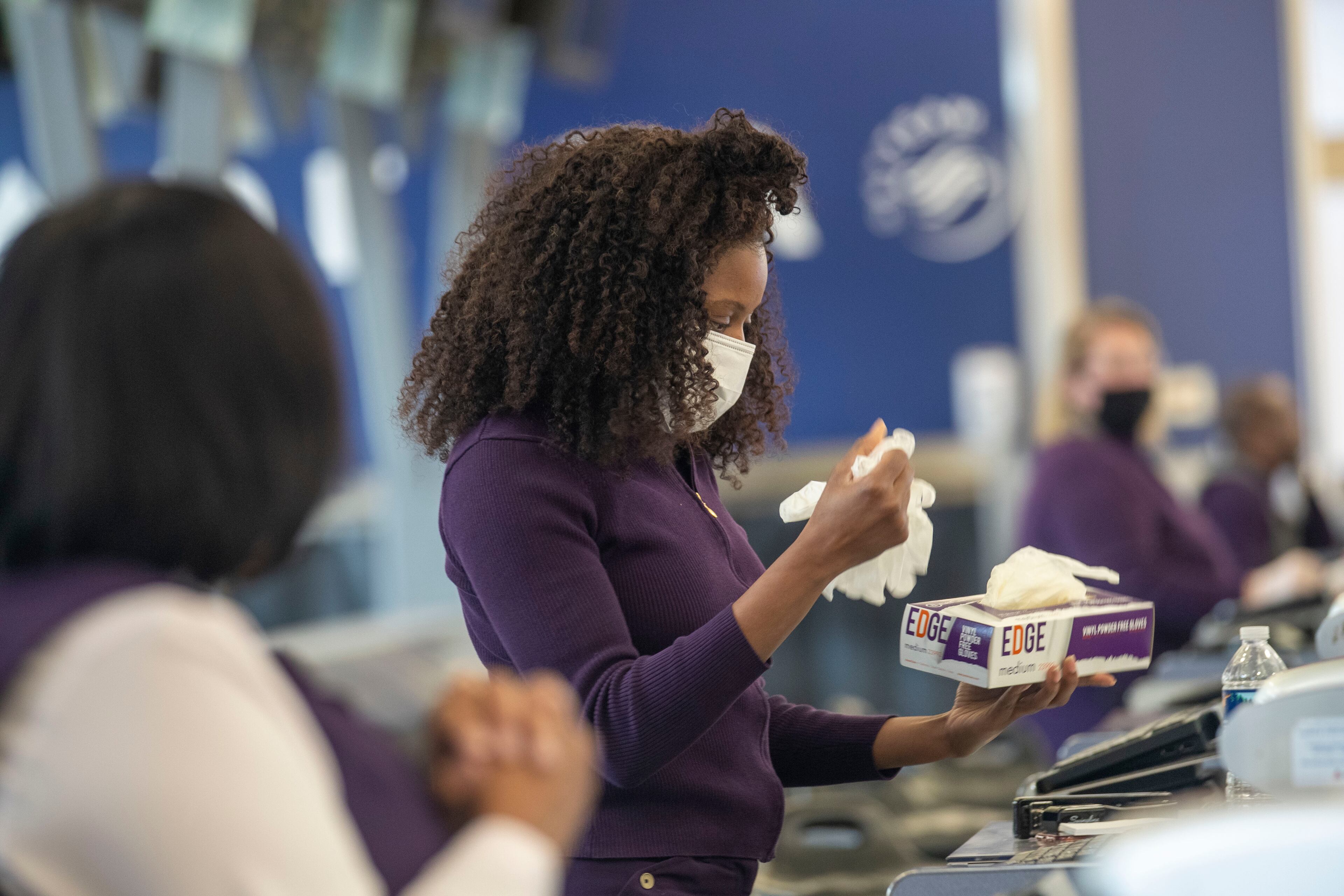 04/28/2020 - Atlanta, Georgia - Delta Air Lines customer service agent Kim Franklin retrieves a new pair of disposable gloves after working with a customer during her shift at a Delta Air Lines ticket counter inside Atlanta's Hartsfield-Jackson International Airport, Tuesday, April 28, 2020. (ALYSSA POINTER / ALYSSA.POINTER@AJC.COM)