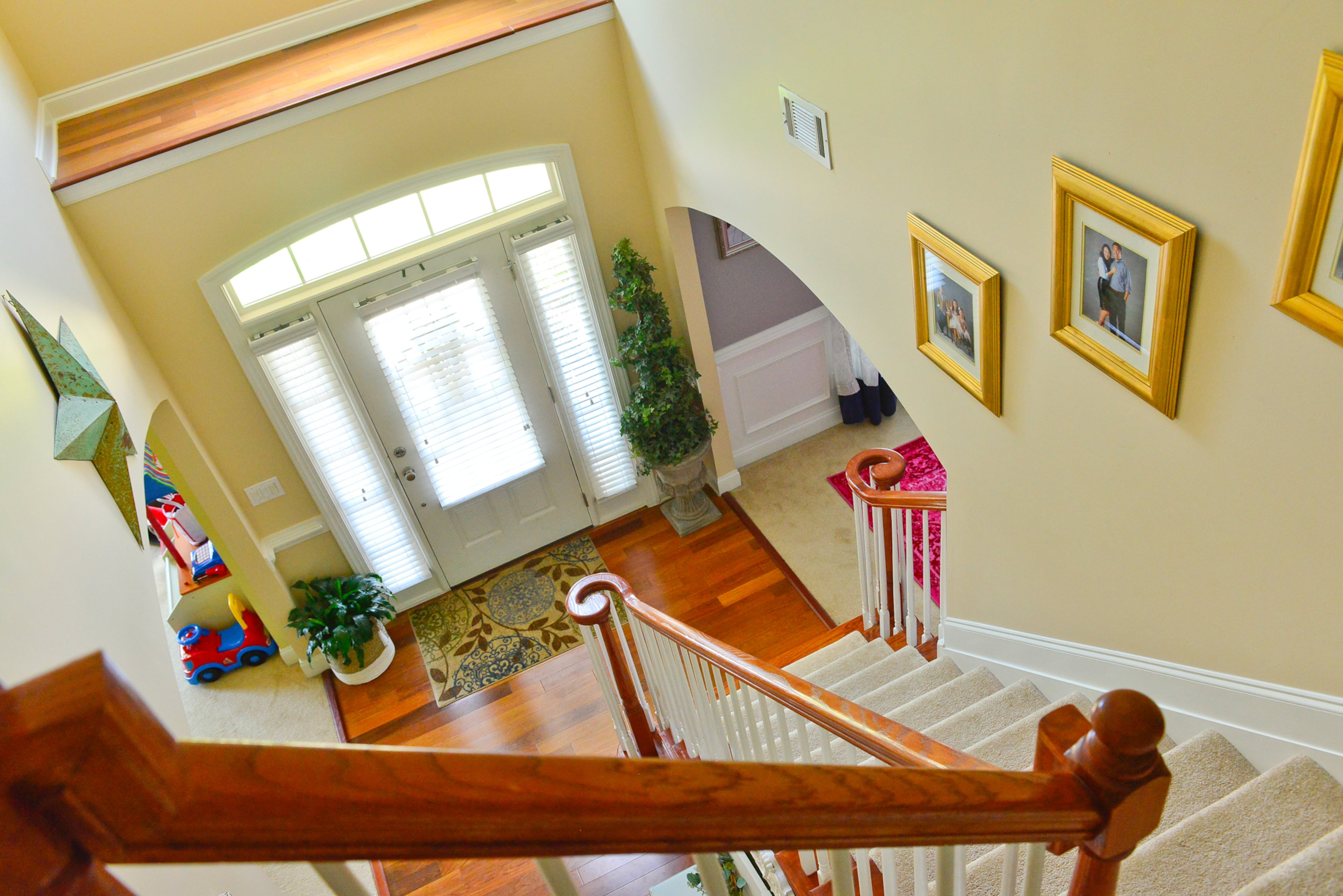 Foyer: The family loves the two staircases in their Cumming home that lead up to a central landing. This view shows homeowner Yuni Min's characteristic pop of gold in her decorating. Many of the picture frames in the home come from thrift stores, and Yuni paints them to match.
