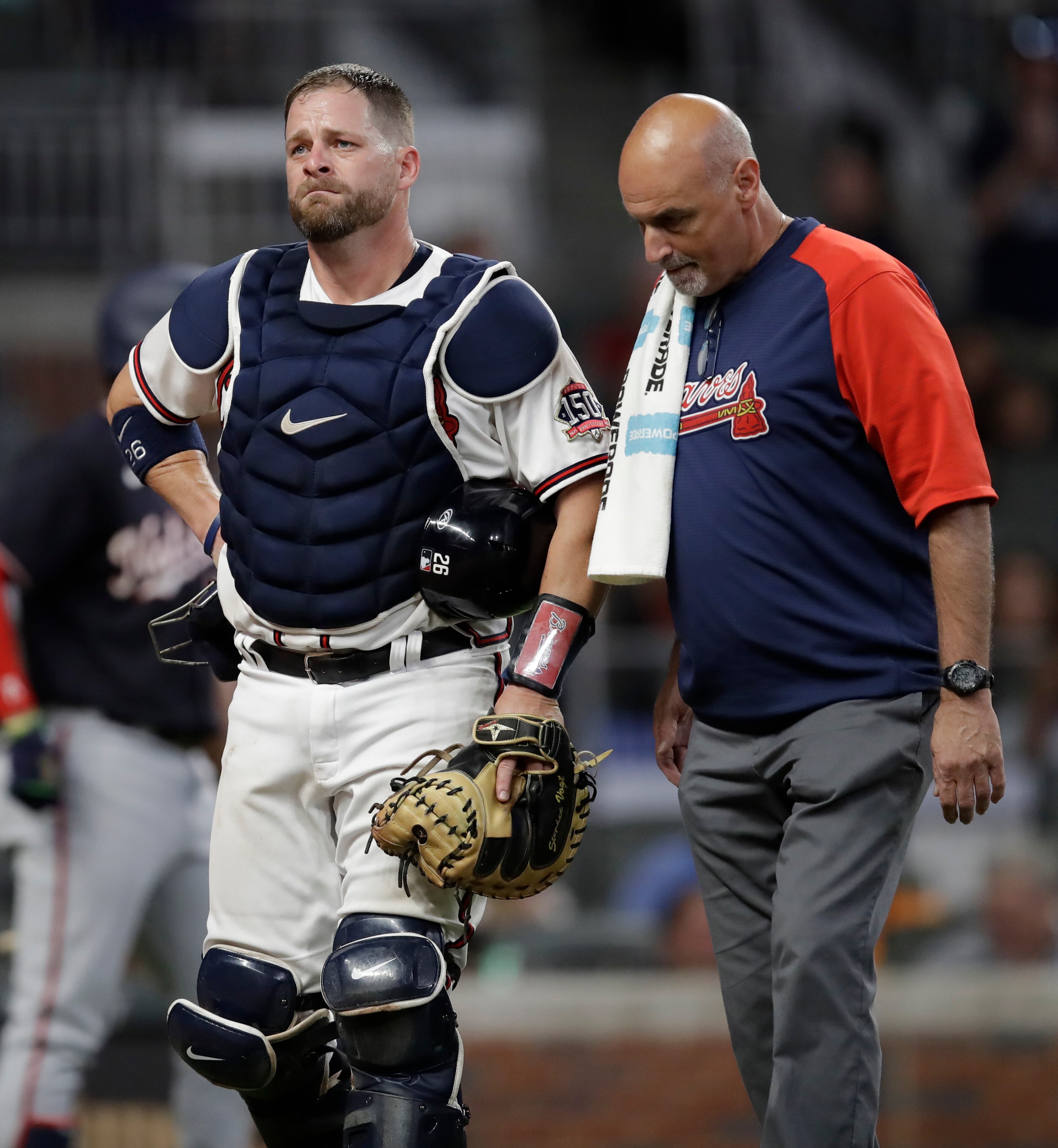 Atlanta Braves' Stephen Vogt, left, walks beside a trainer in the seventh inning of a baseball game against the Washington Nationals, Thursday, Sept. 9, 2021, in Atlanta. Vogt left the game with a leg injury. (AP Photo/Ben Margot)