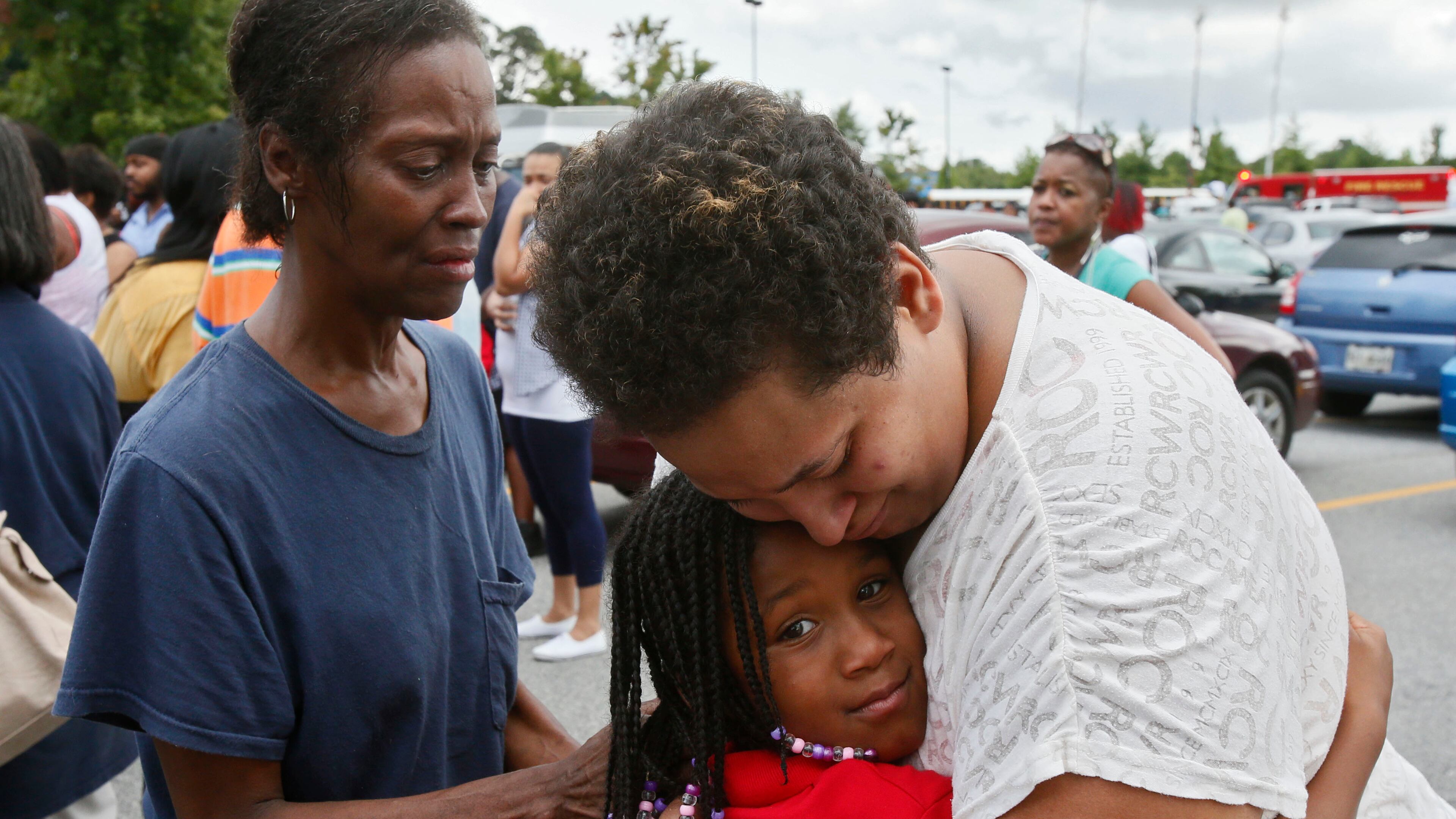 In 2013, A'Reunia Johnson, 9, gets a hug from her mother, Lecretia White, and her grandmother, Sheriza Ellis, after a gunman entered the Ronald E. McNair Discovery Learning Academy in DeKalb County and fired six rounds in a front office before surrendering to police. (Bob Andres / AJC file photo)