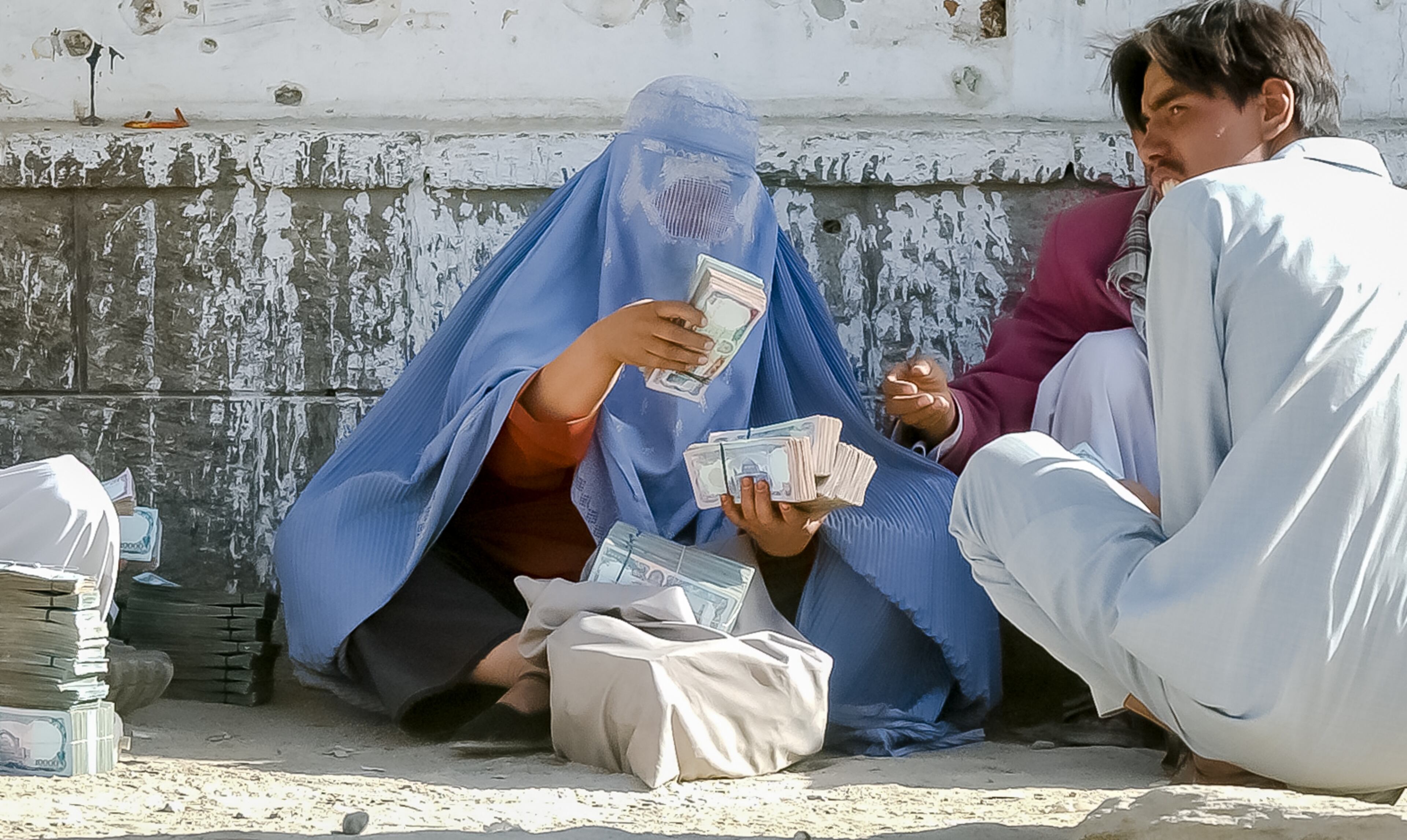 KABUL, AFGHANISTAN: Money changer Shakilla counts stacks of Afghan money in Kabul's main bazaar Saturday, Sept. 7, 2002. As a woman, Shakilla is an anomaly in Kabul's money-changing market; no one asked had ever heard of a woman money changer before. (Bita Honarvar / The Atlanta Journal-Constitution)