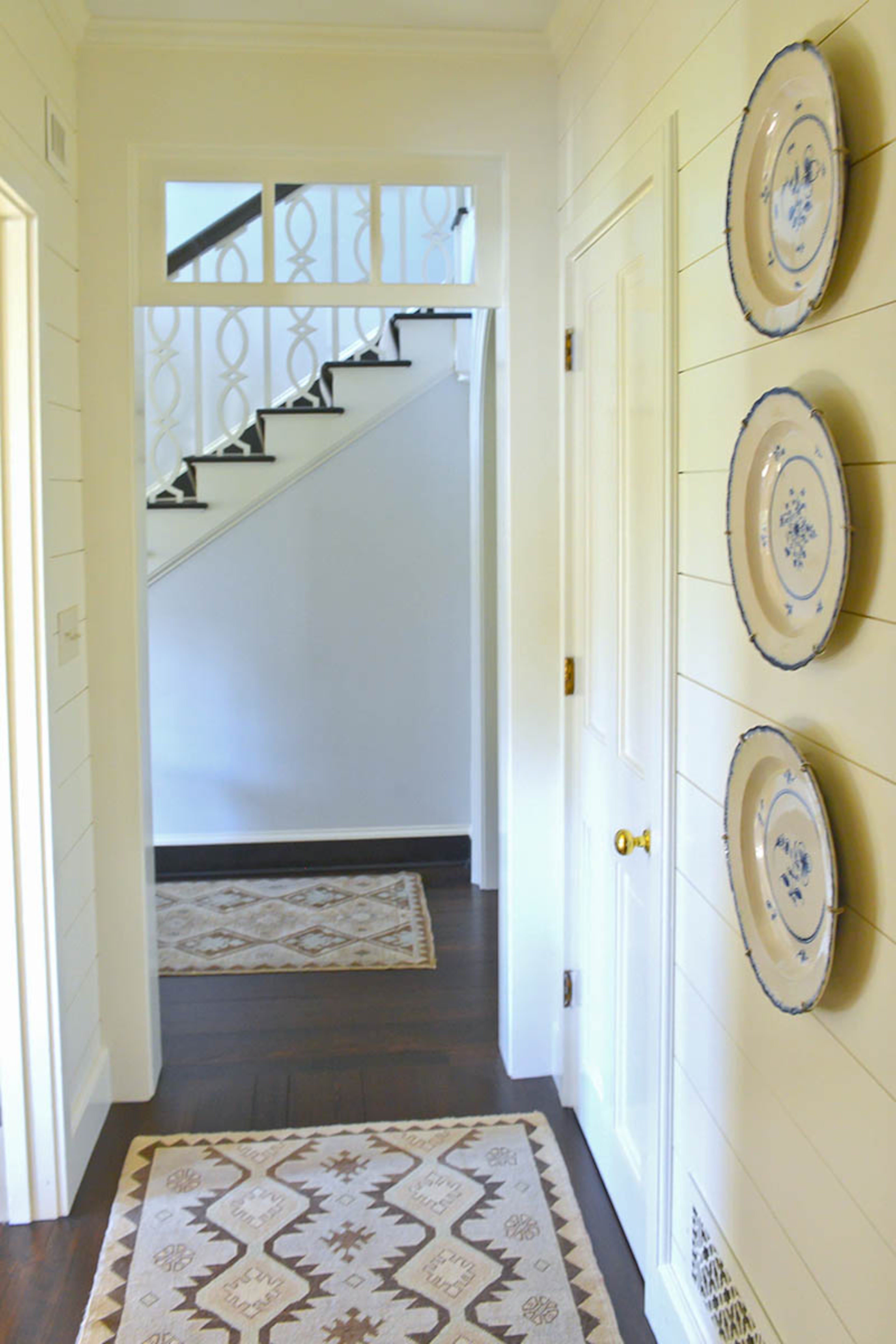 Transoms and painted walls update the interiors of the 1938 home. Rugs add pattern and comfort to the hardwood floors.
