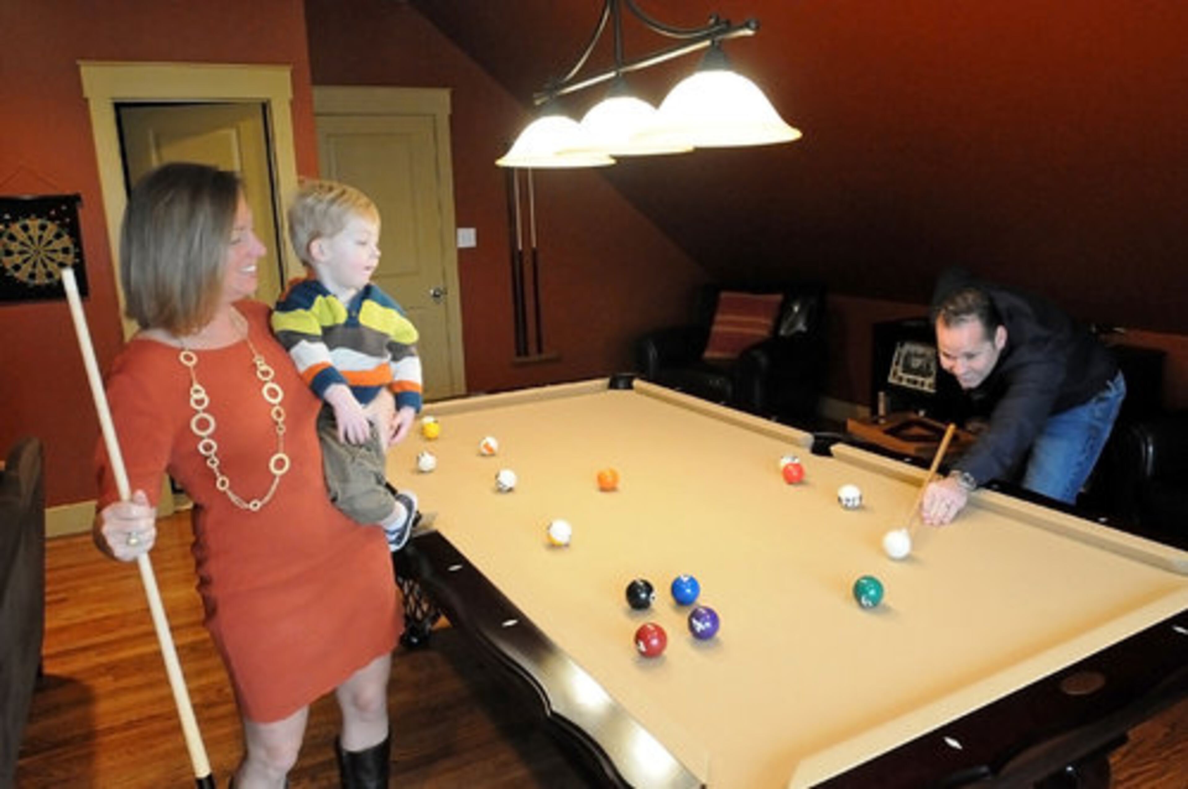 The game room's color palette pulls together deep red and green accents and mustard-color trim, which matches the pool table. The couple incorporated Old World-style pieces, such as a globe from an antique store in Marietta opens up to a mini bar.